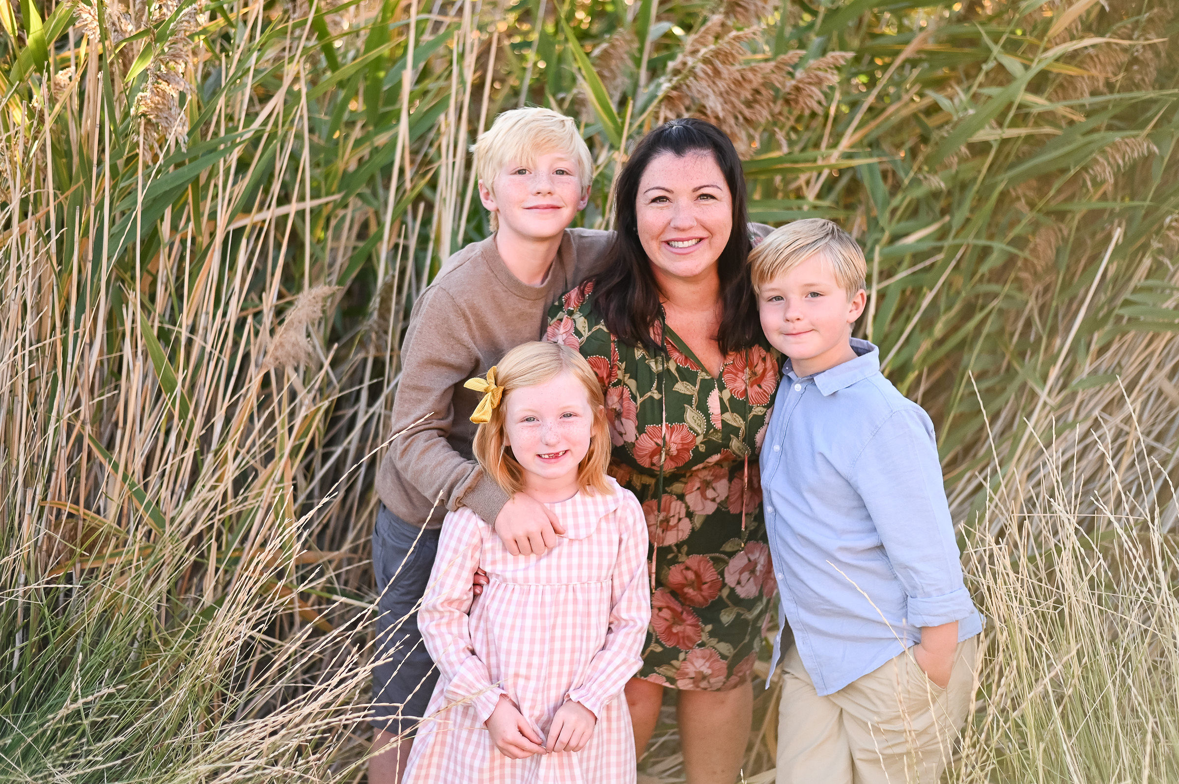 Family smiling and wrapping arms around one another at Tunnel Springs Park in Utah.