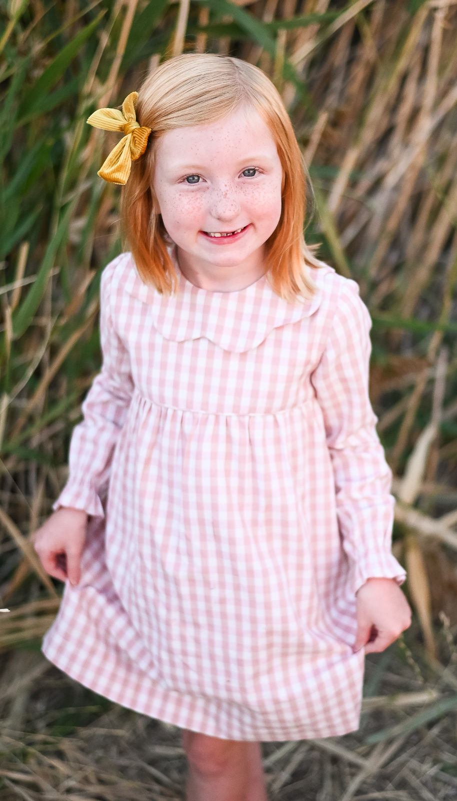 Little girl smiling on while holding her dress at golden hour in Tunnel Springs Park.