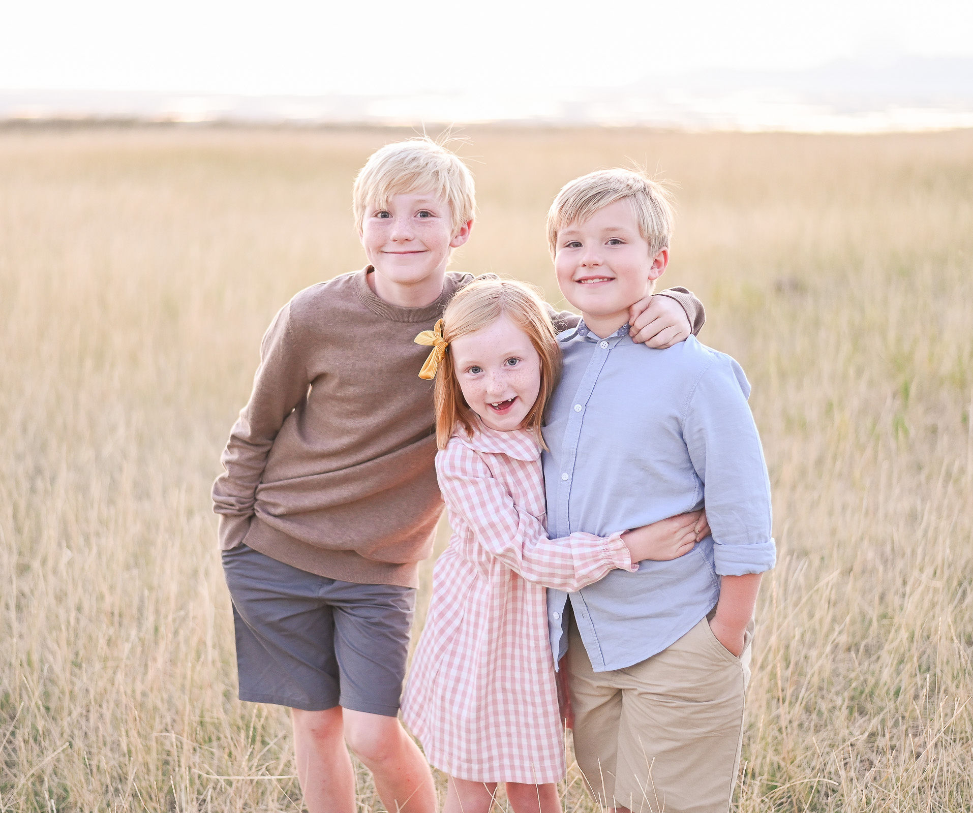 Smiling kids embracing one another at Tunnel Springs Park in Utah at golden hour.