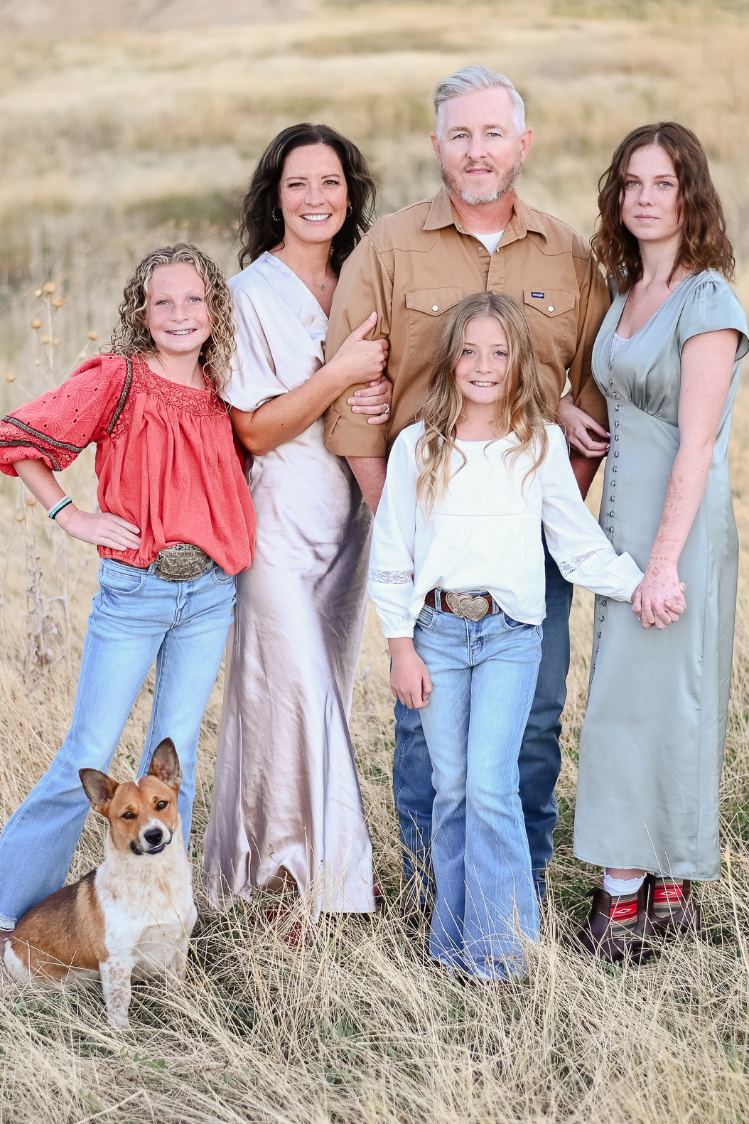Family in the tall grasses with their dog in the foothills of the mountains of Mapleton Utah.