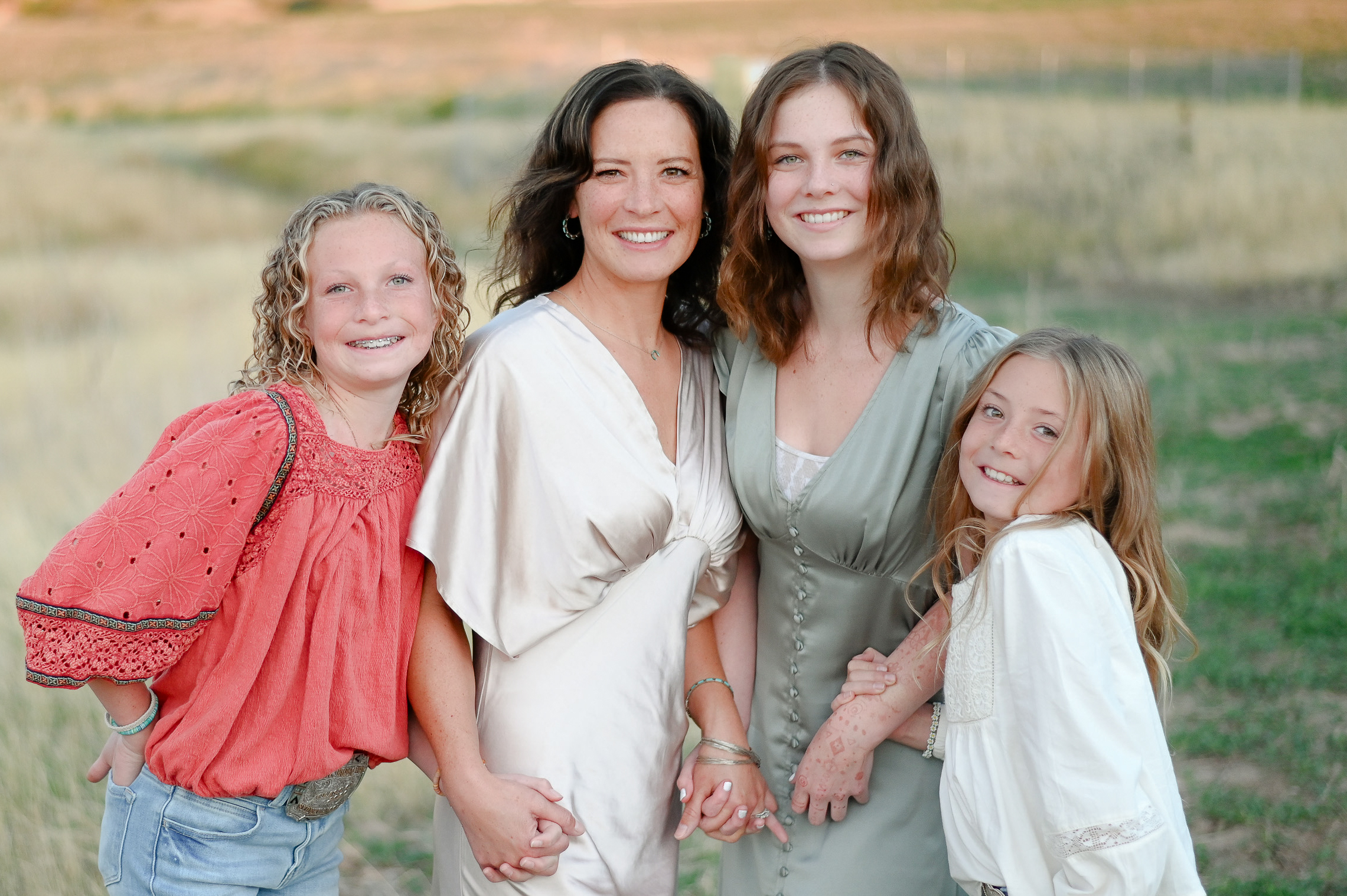 Dad smiles hand in hand with his daughters in the foothills of the mountains in Mapleton Utah.
