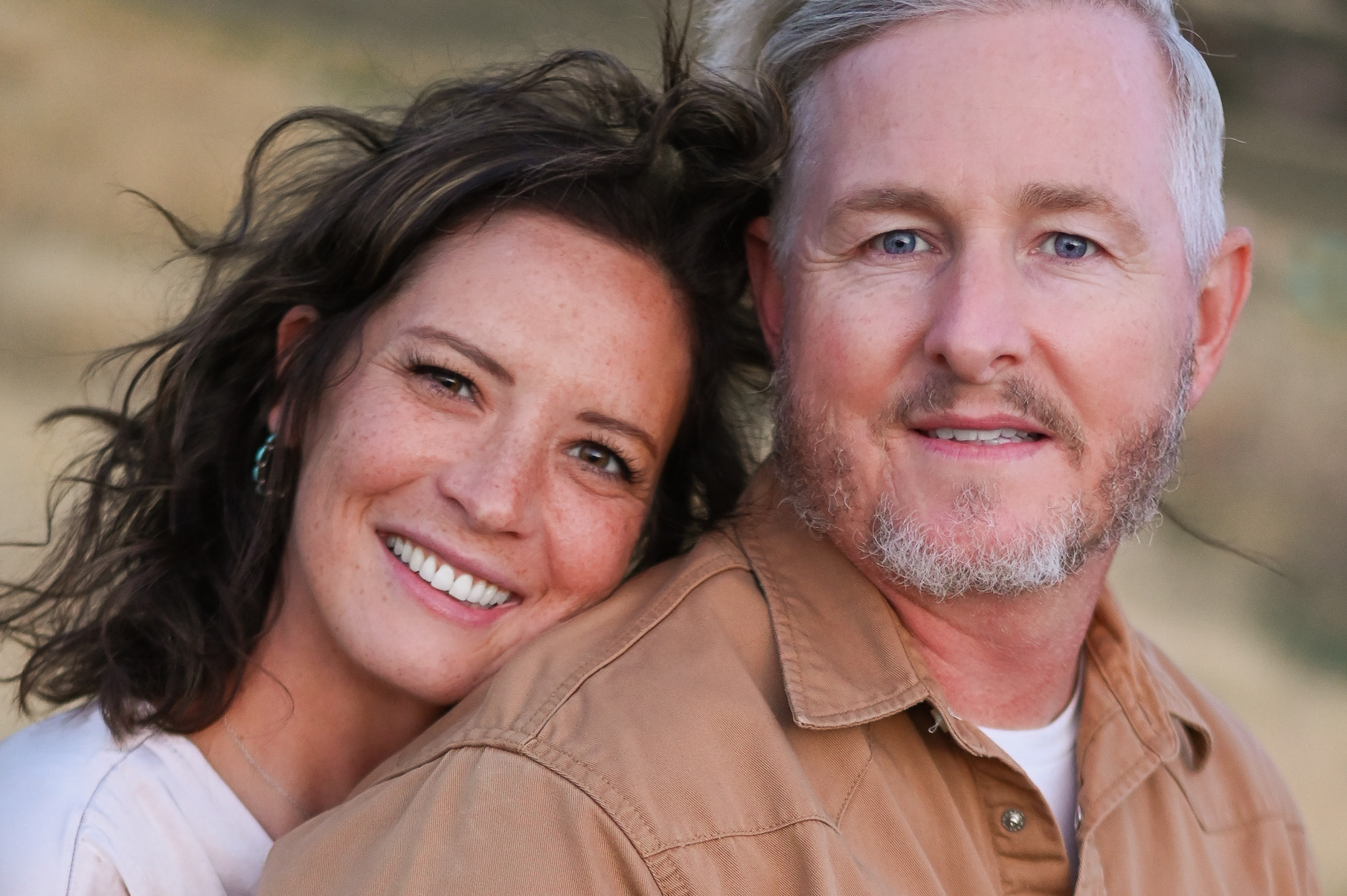 A couple embracing one anotherwith smiles on their faces in the foothills of the mountains in Mapleton Utah.