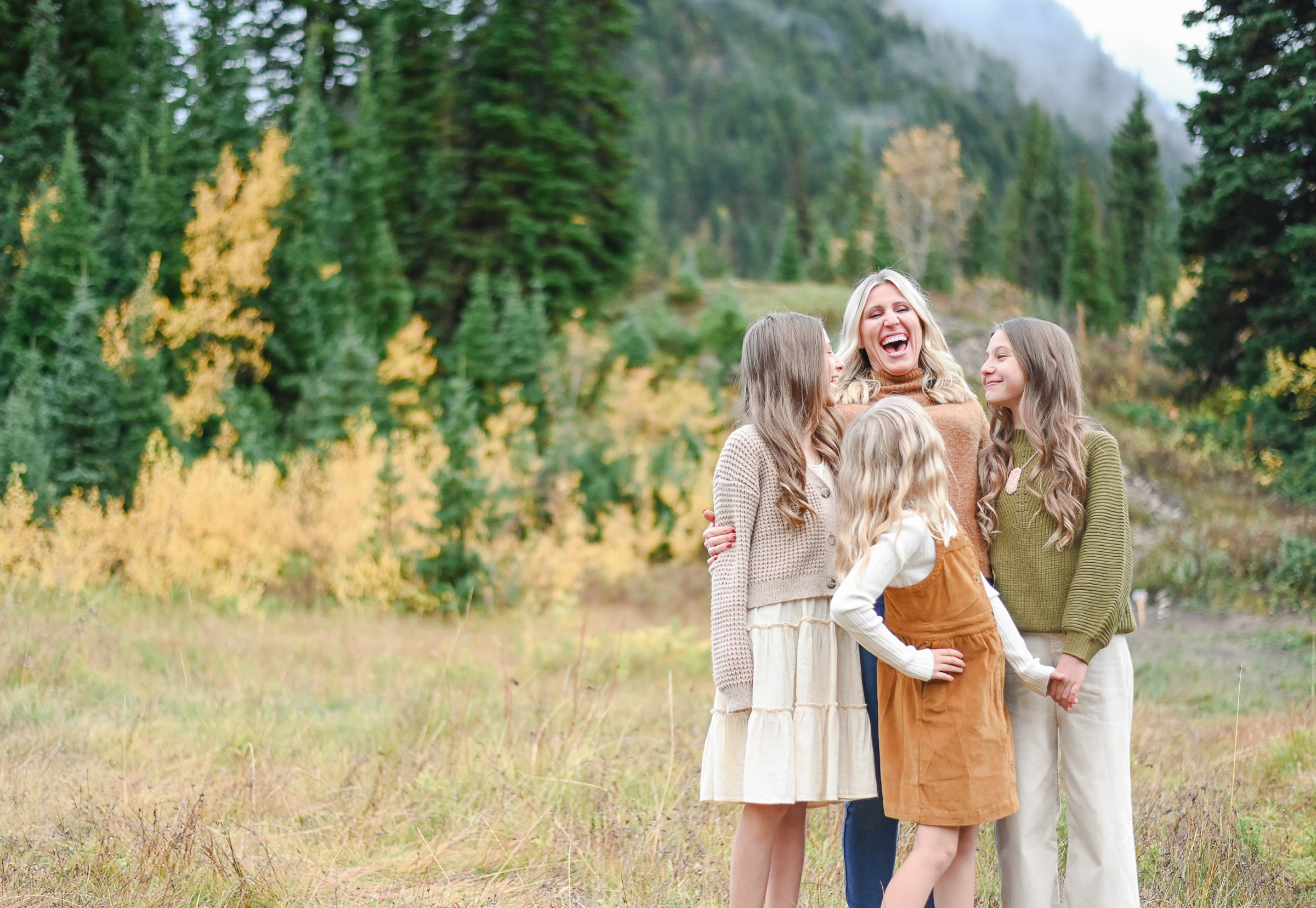 Mom laughing with her beautiful girls in the fall foliage of Big Cottonwood Canyon in Utah. Fall family photos in Cottonwood Canyon