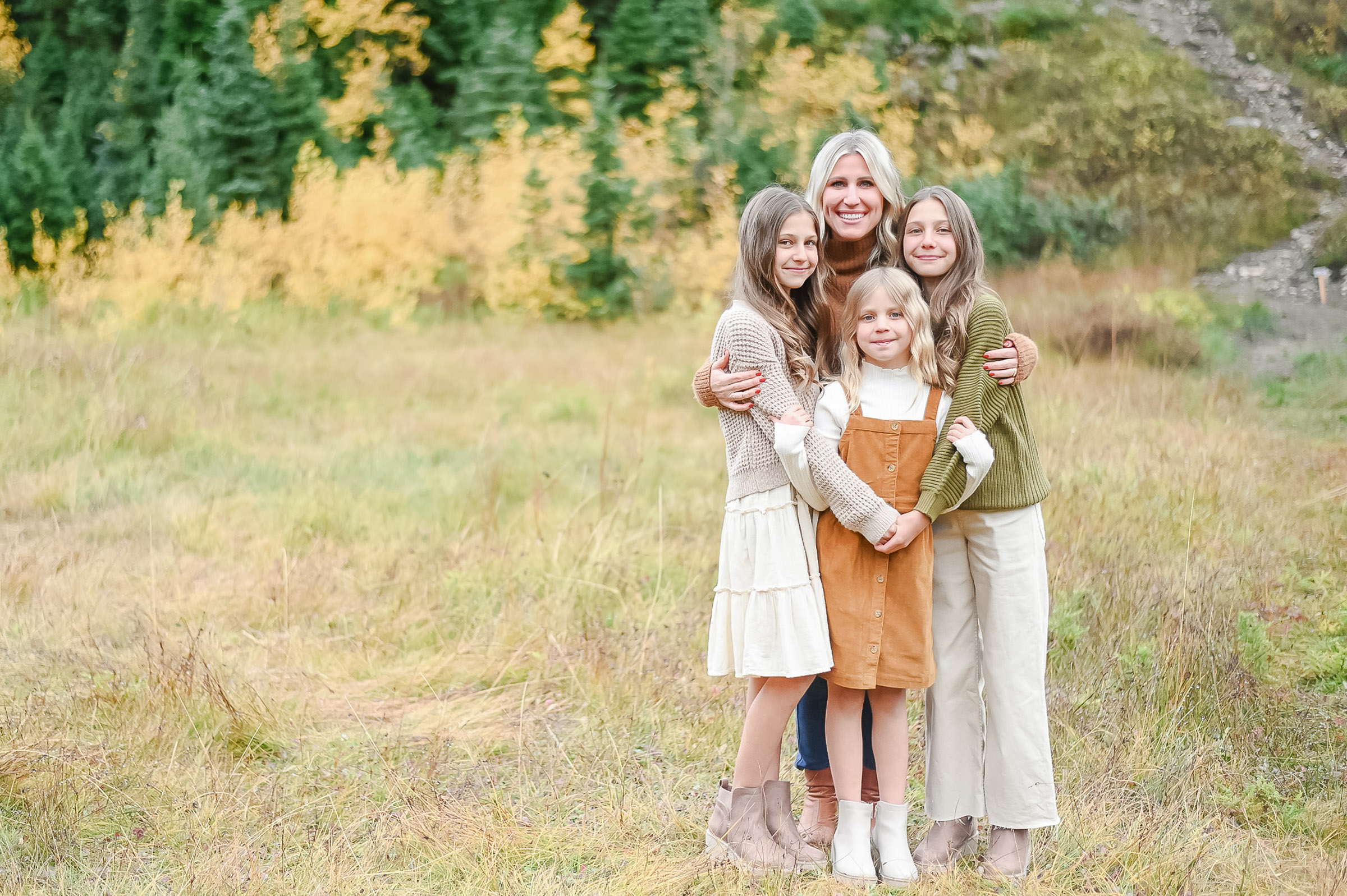 Mom smiling with her beautiful girls in the fall foliage of Big Cottonwood Canyon in Utah. Fall family photos in Cottonwood Canyon