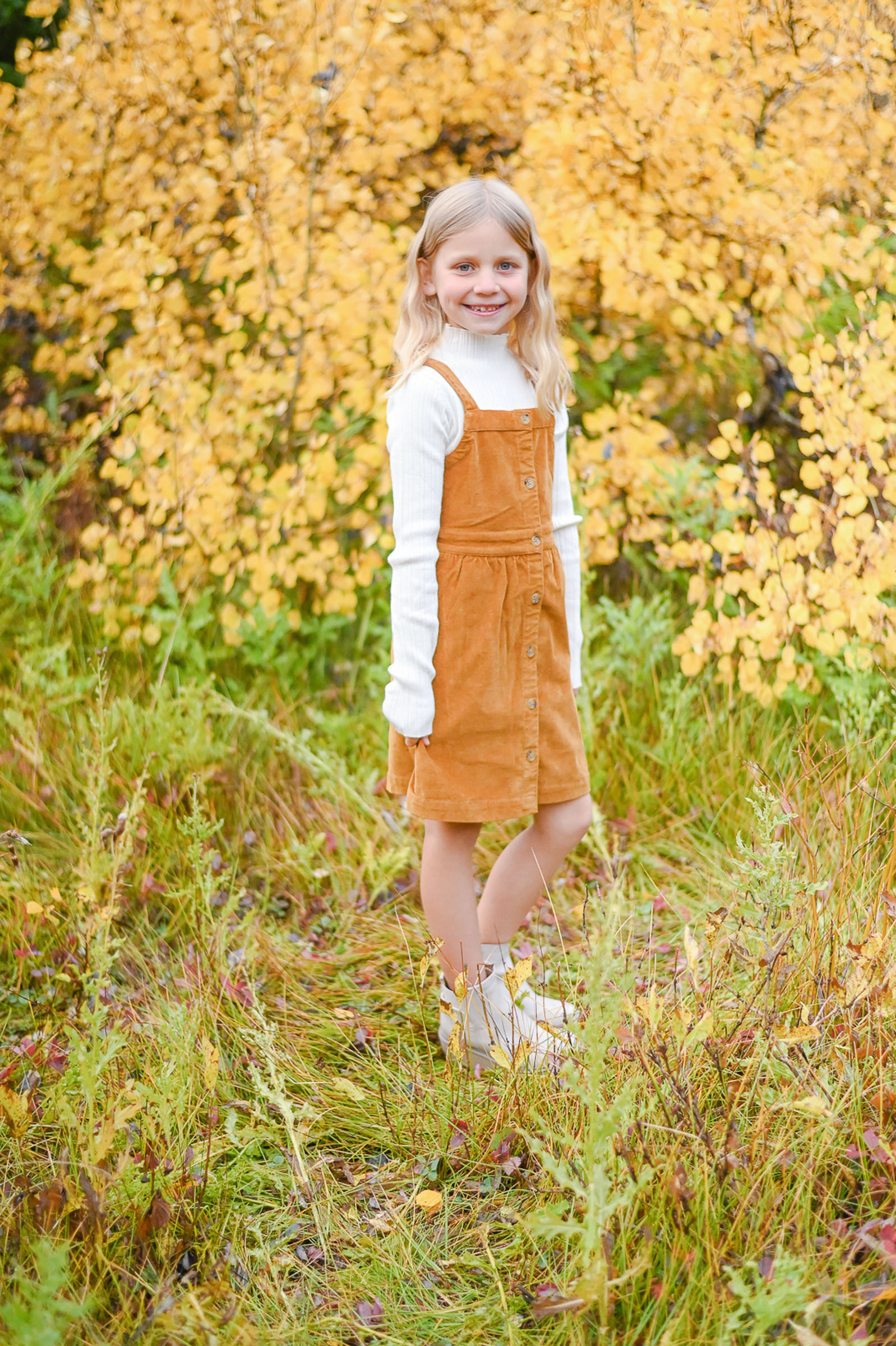 Darling girl holding her dress as she takes her moment to shine in the fall leaves of Cottonwod Canyon Utah.Fall family photos in Cottonwood Canyon.