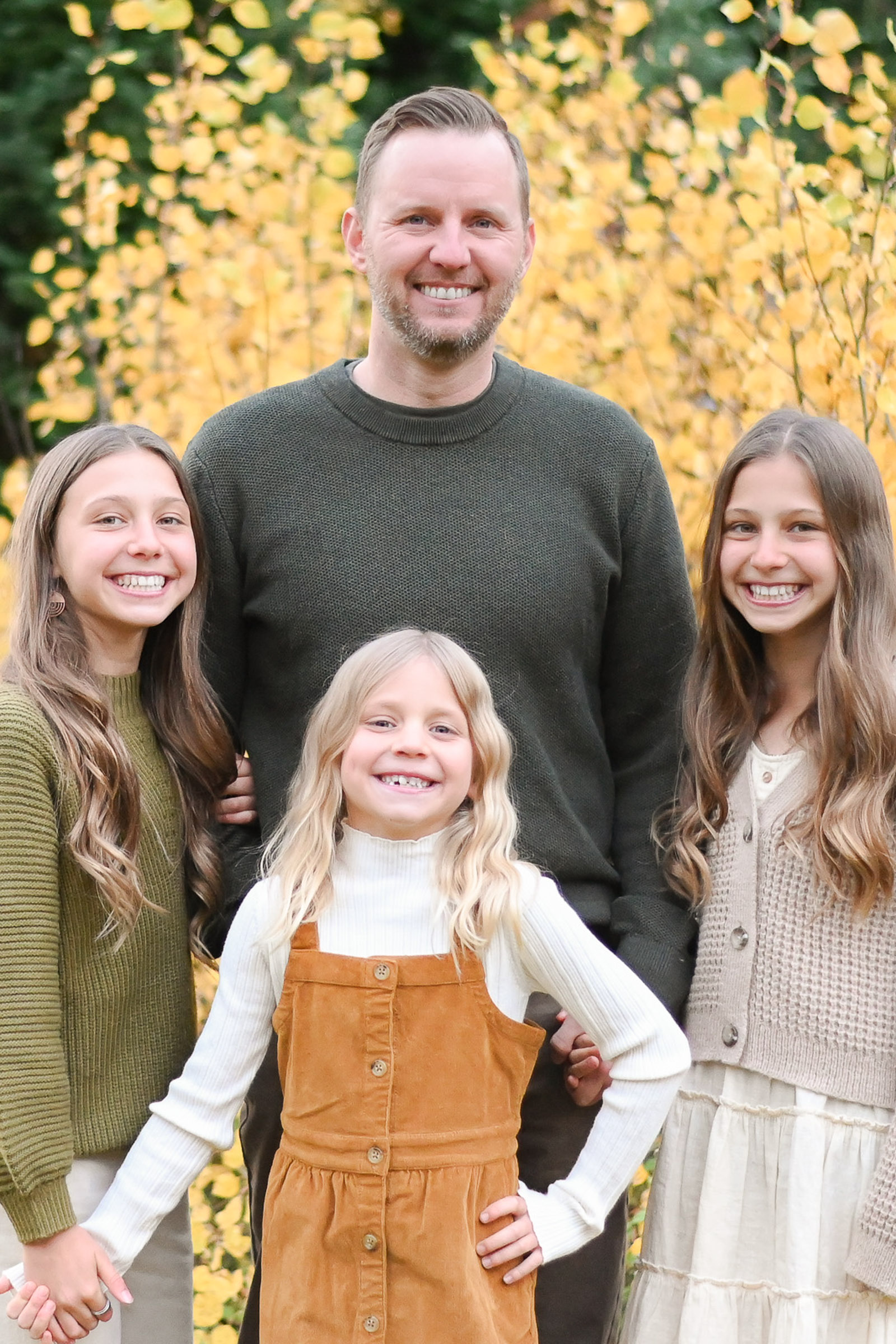 Step Dad smiling with his beautiful step daughters in the fall foliage of Big Cottonwood Canyon in Utah. Fall family photos in Cottonwood Canyon