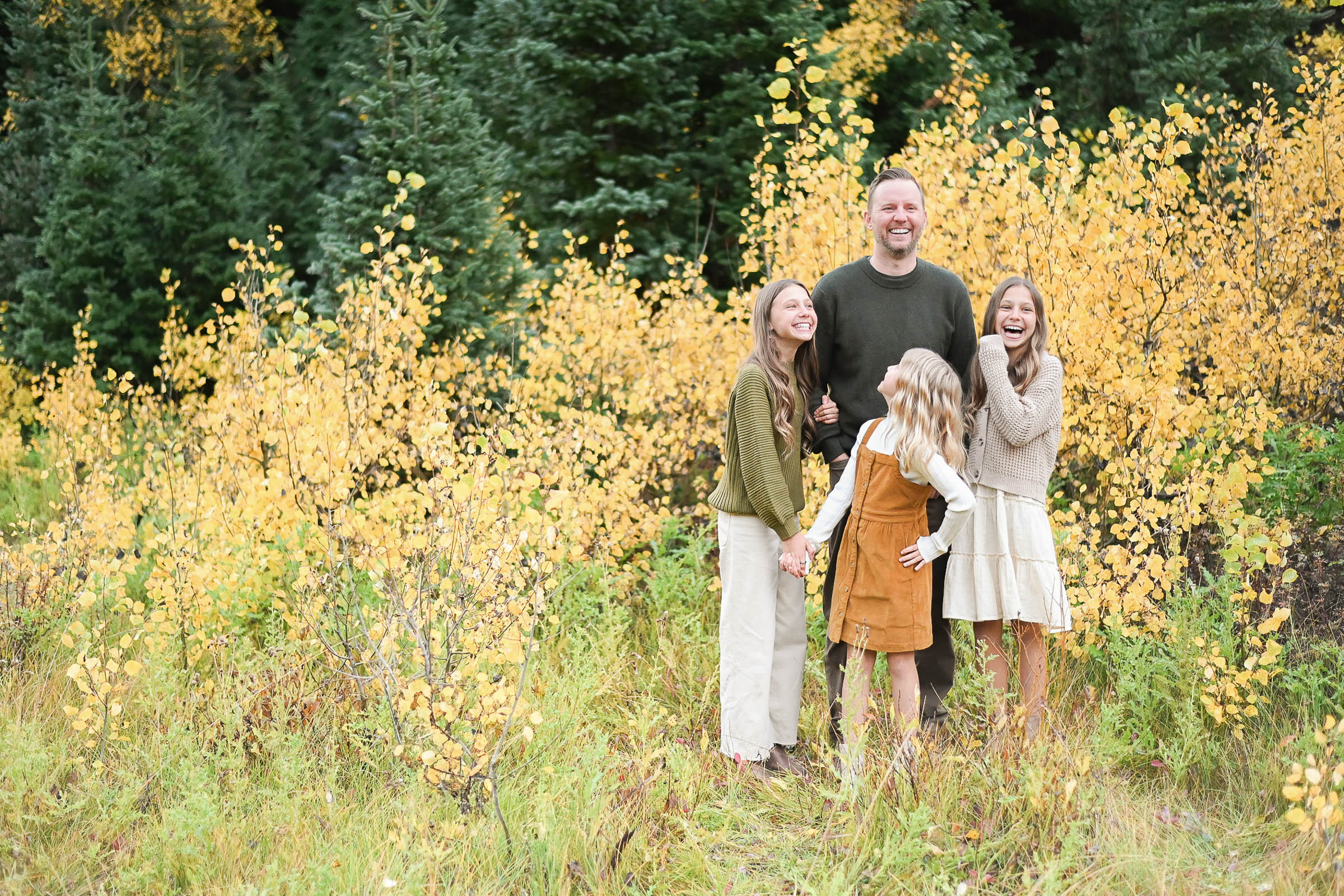 Step Dad laughing with his beautiful step daughters in the fall foliage of Big Cottonwood Canyon in Utah. Fall family photos in Cottonwood Canyon