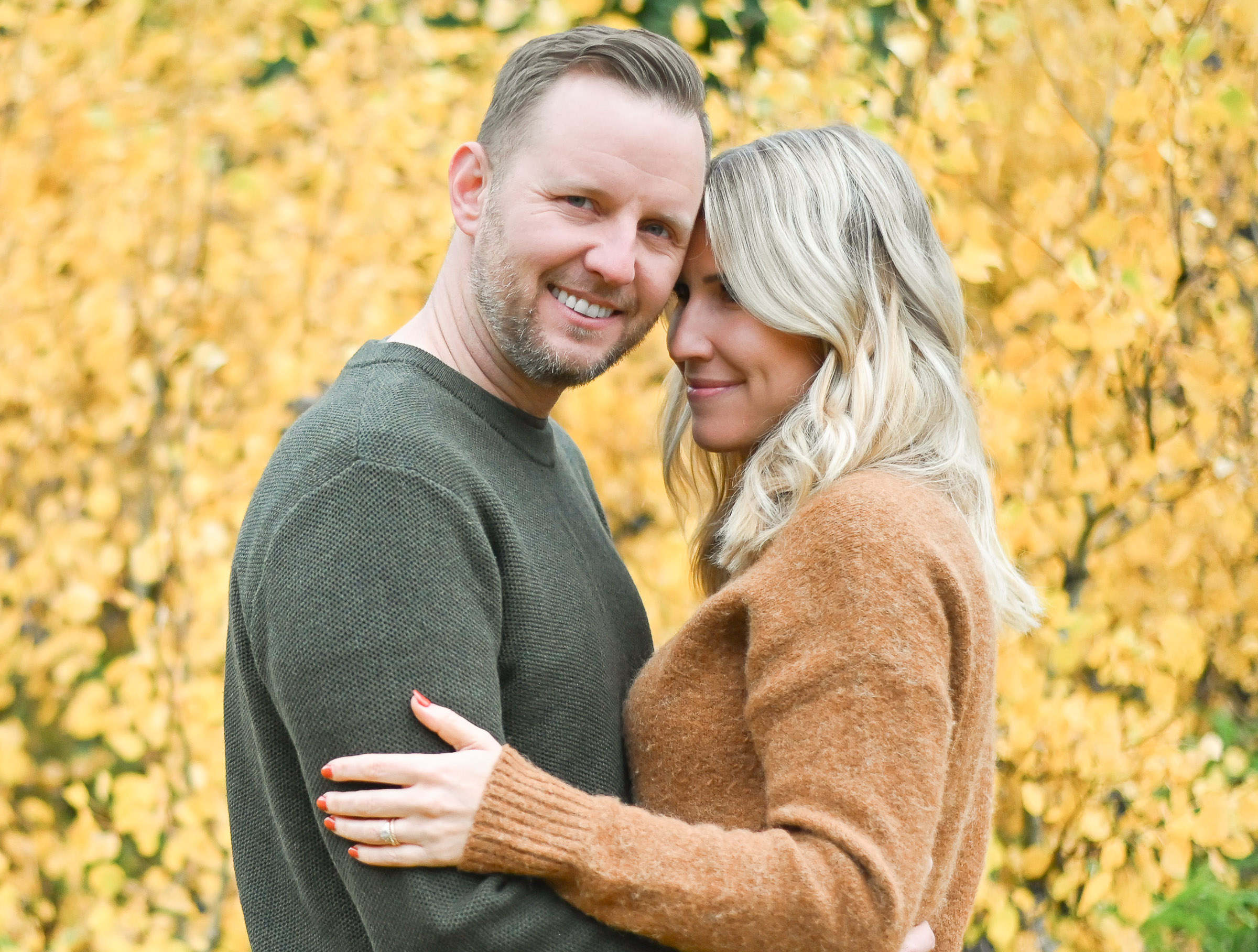 Cute wife looking at her newly married husband as he smiles for the camera in crisp fall air of Cottonwood Canyon Utah. Fall family photos in Cottonwood Canyon
