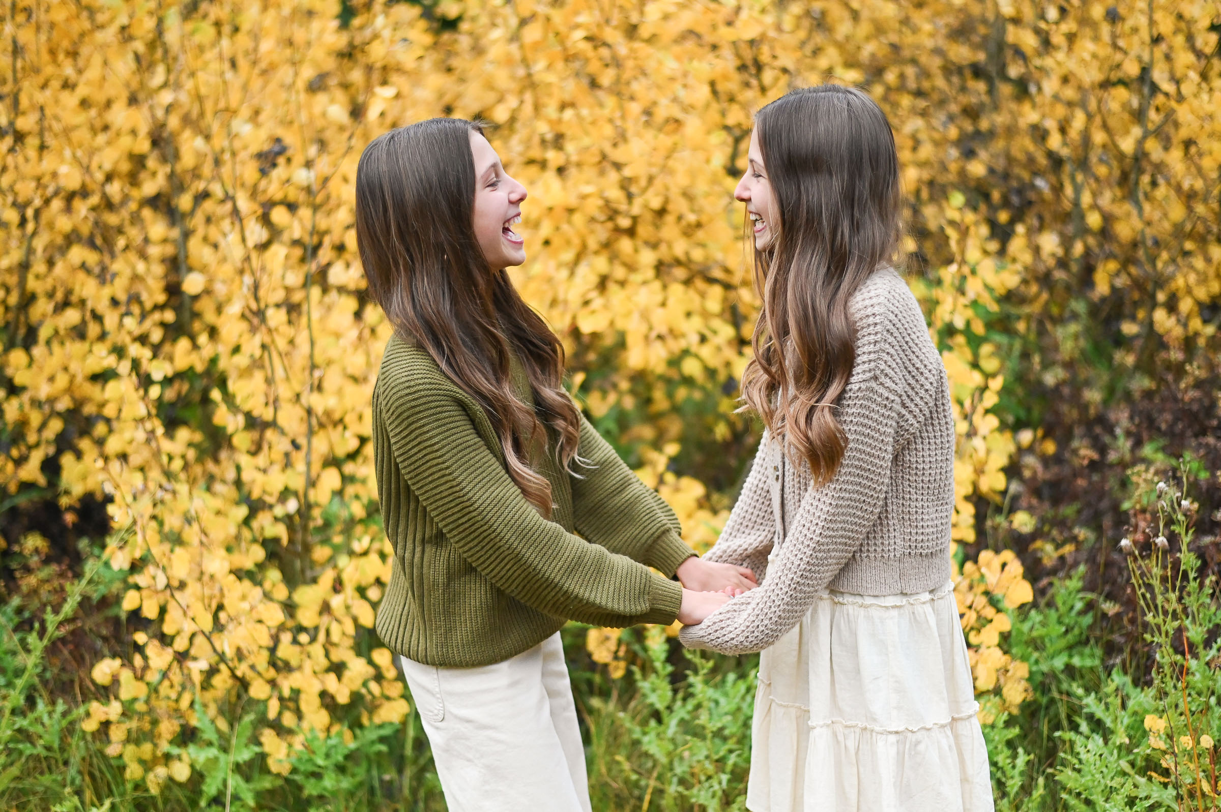 Twin girls smiling and having fun in front of the golden fall leaves of Cottonwood Canyon in Utah.