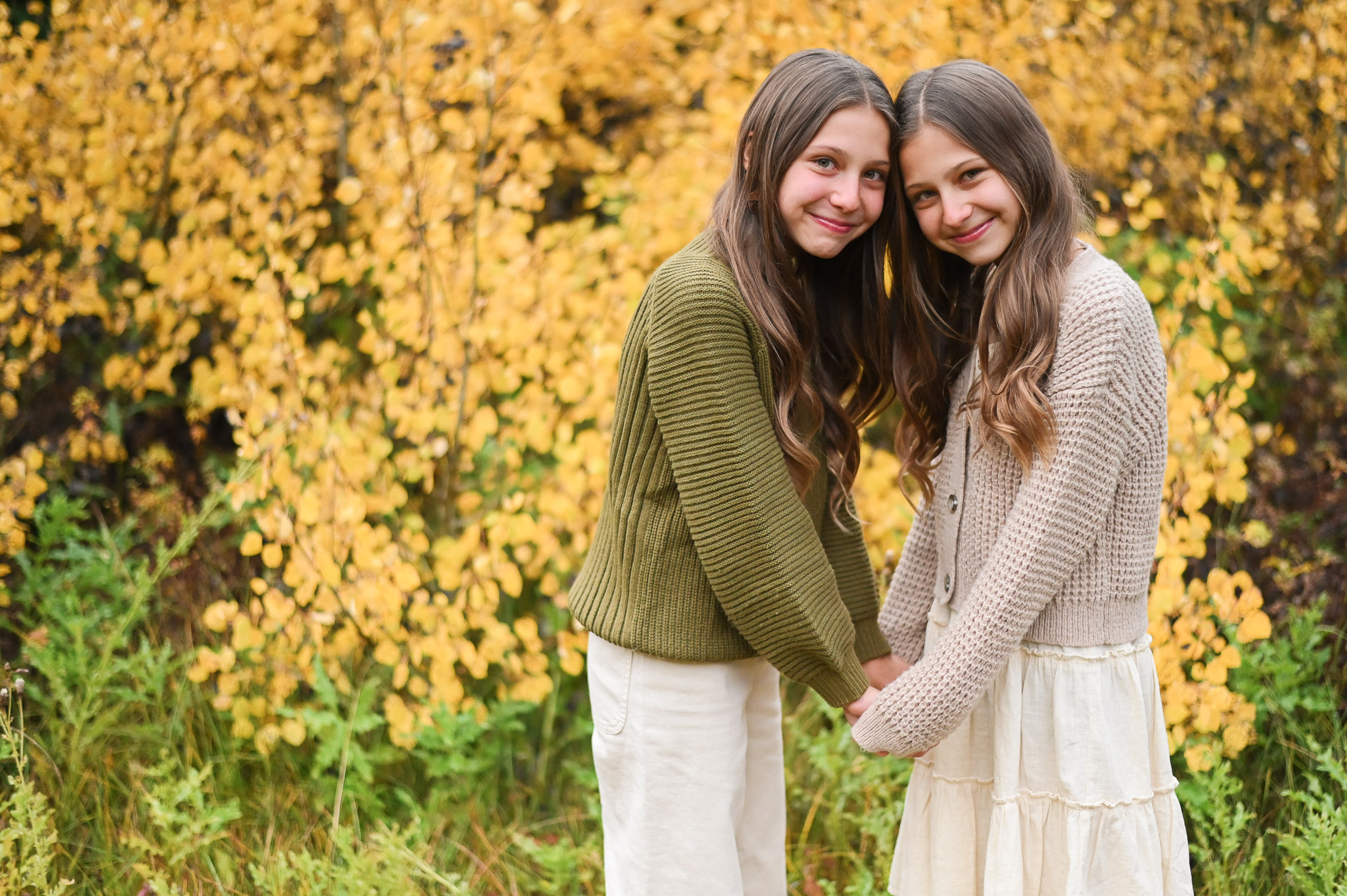 Twin girls smiling and having fun in front of the golden fall leaves of Cottonwood Canyon in Utah. Fall family photos in Cottonwood Canyon