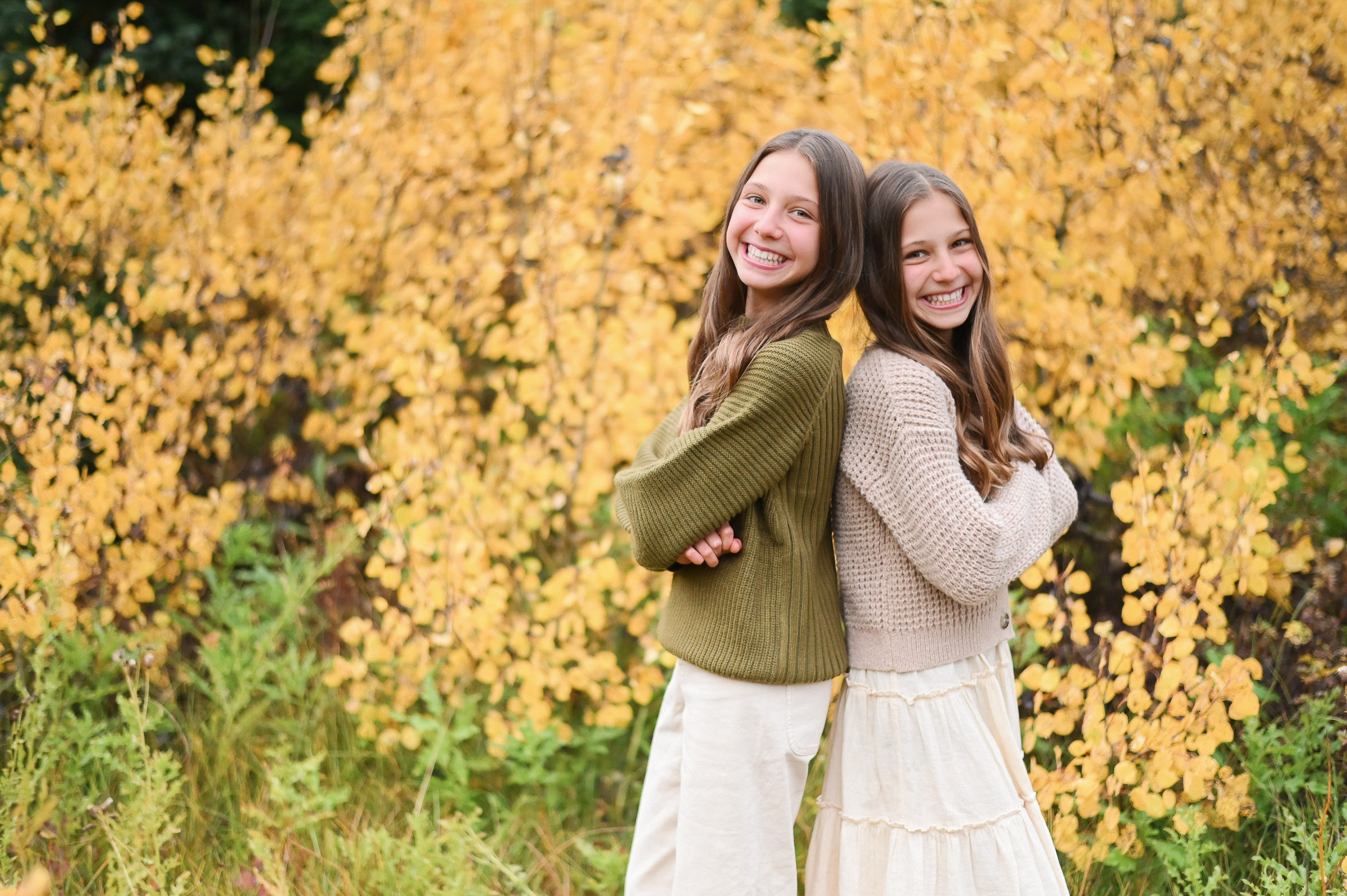Twin girls smiling and having fun in front of the golden fall leaves of Cottonwood Canyon in Utah. Fall family photos in Cottonwood Canyon