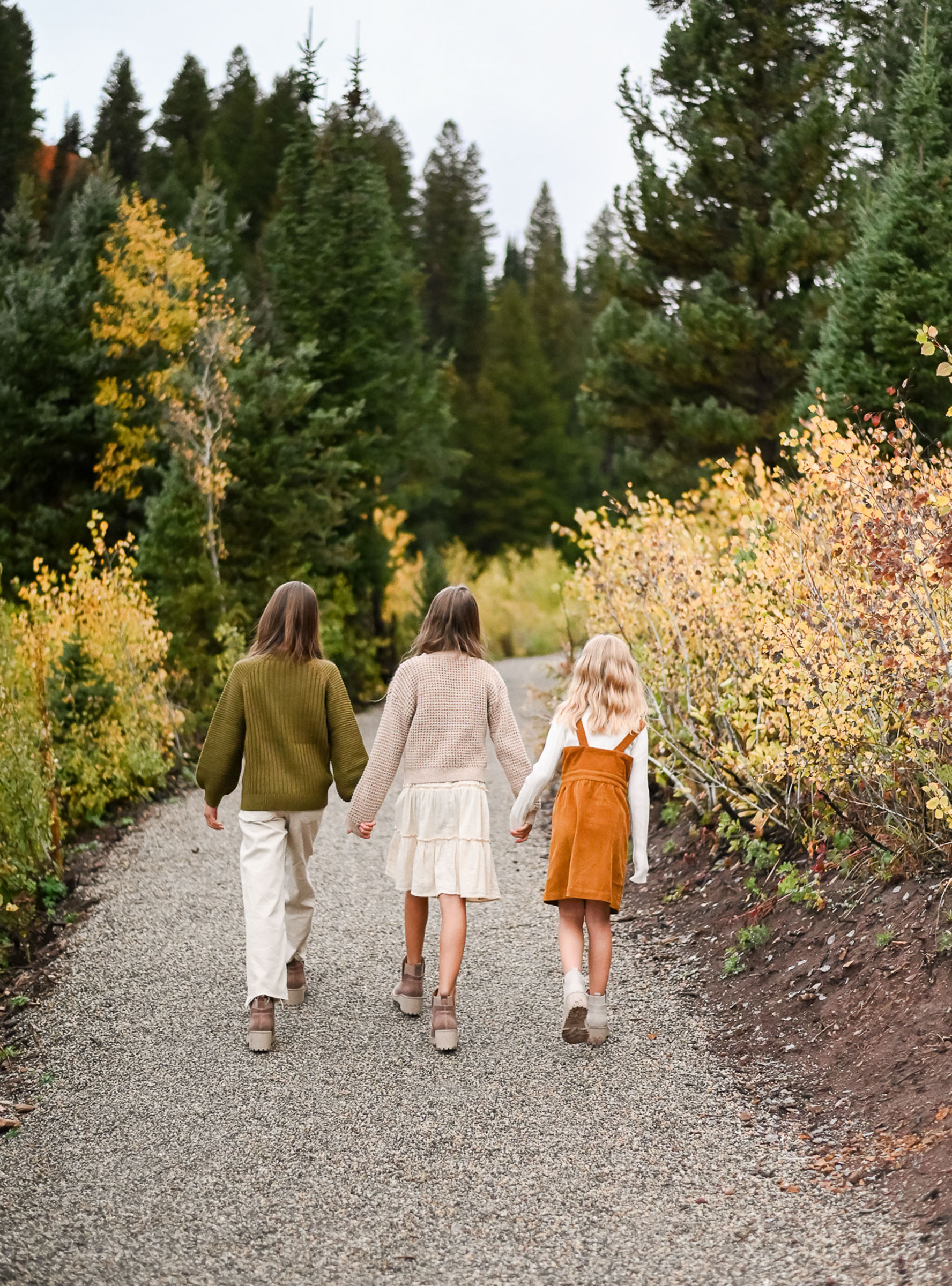 Sisters walk hand in hand on the trails of Big Cottonwood Canyon. Fall family photos in Cottonwood Canyon