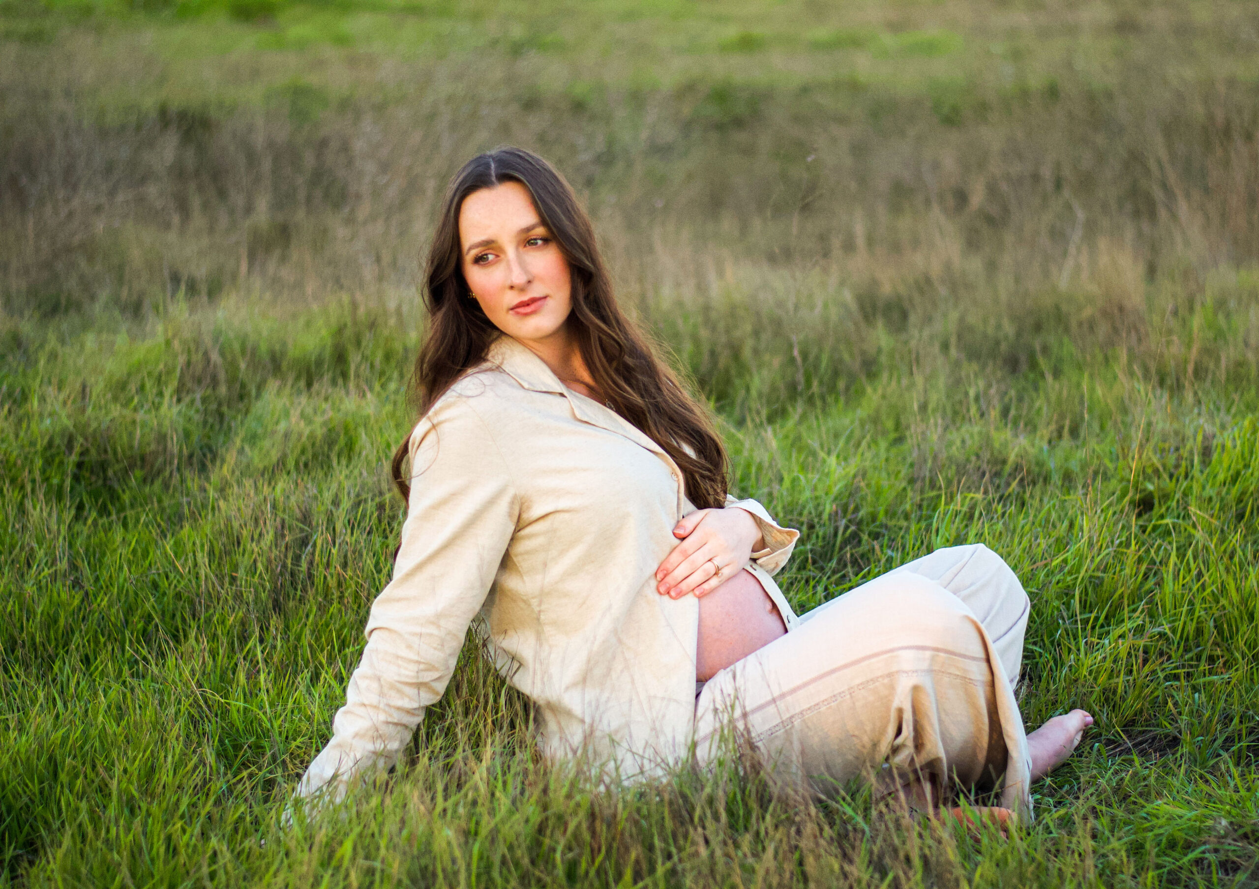Mother to be in a green field for her maternity shoot in Ripon, CA.