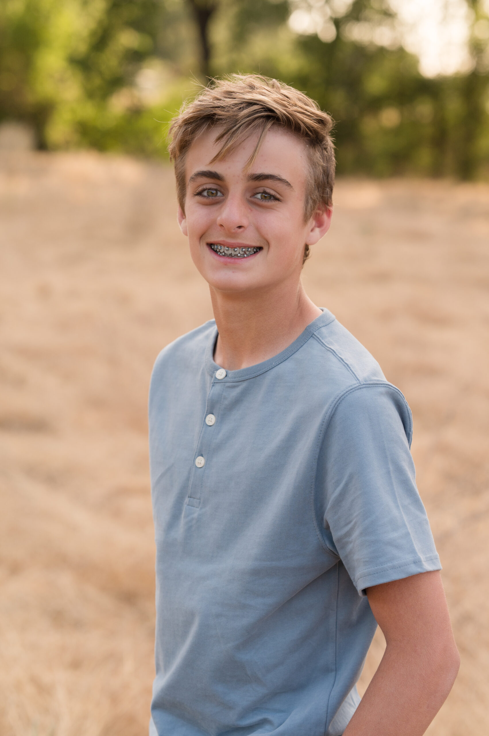 A boy smiling at the camera as he puts on his best posture and pose for his shining moment at Oak Grove Park in Ripon California.