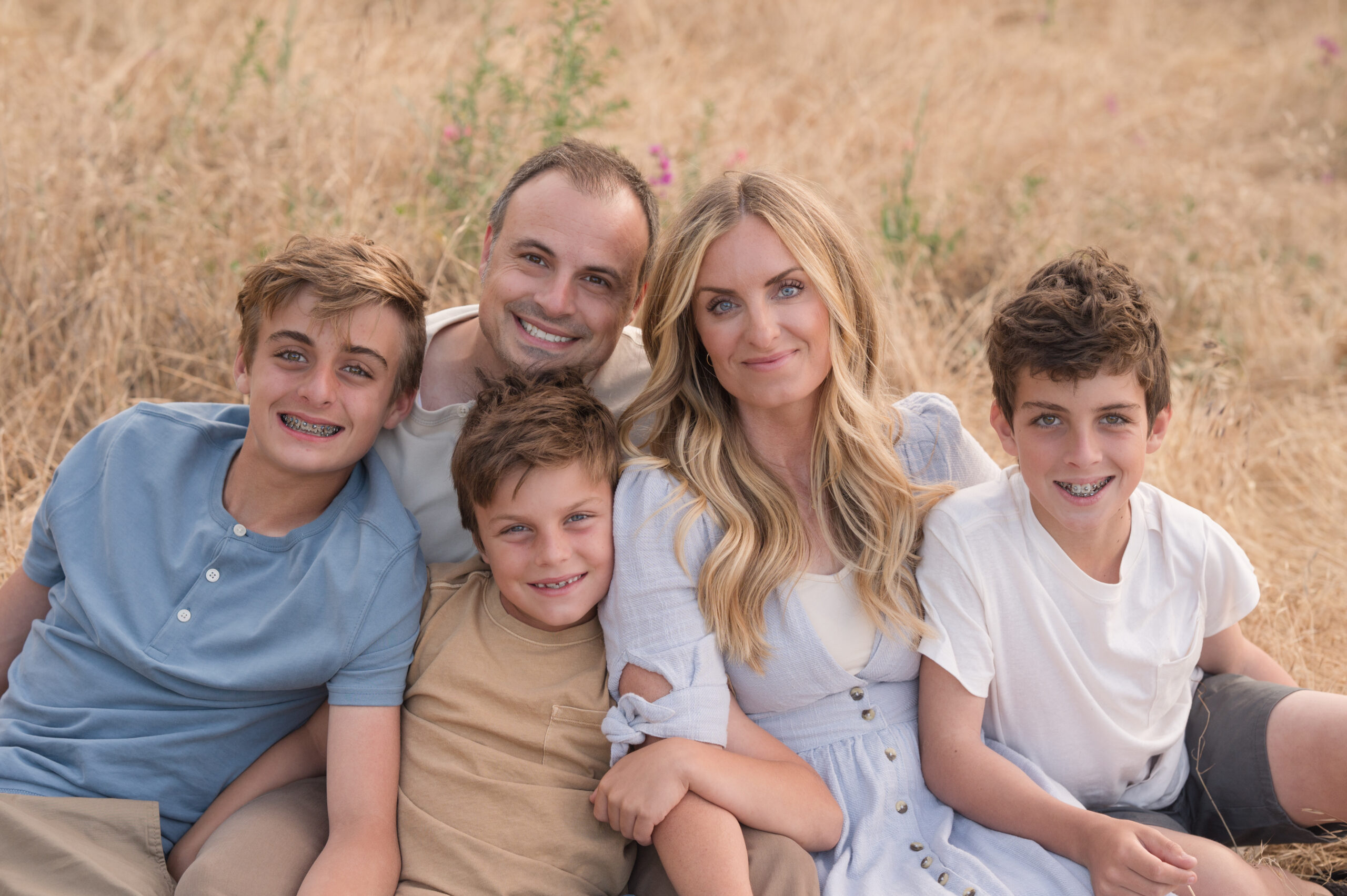Family embracing on the ground in golden hour at Oak Grove Park in Ripon, California