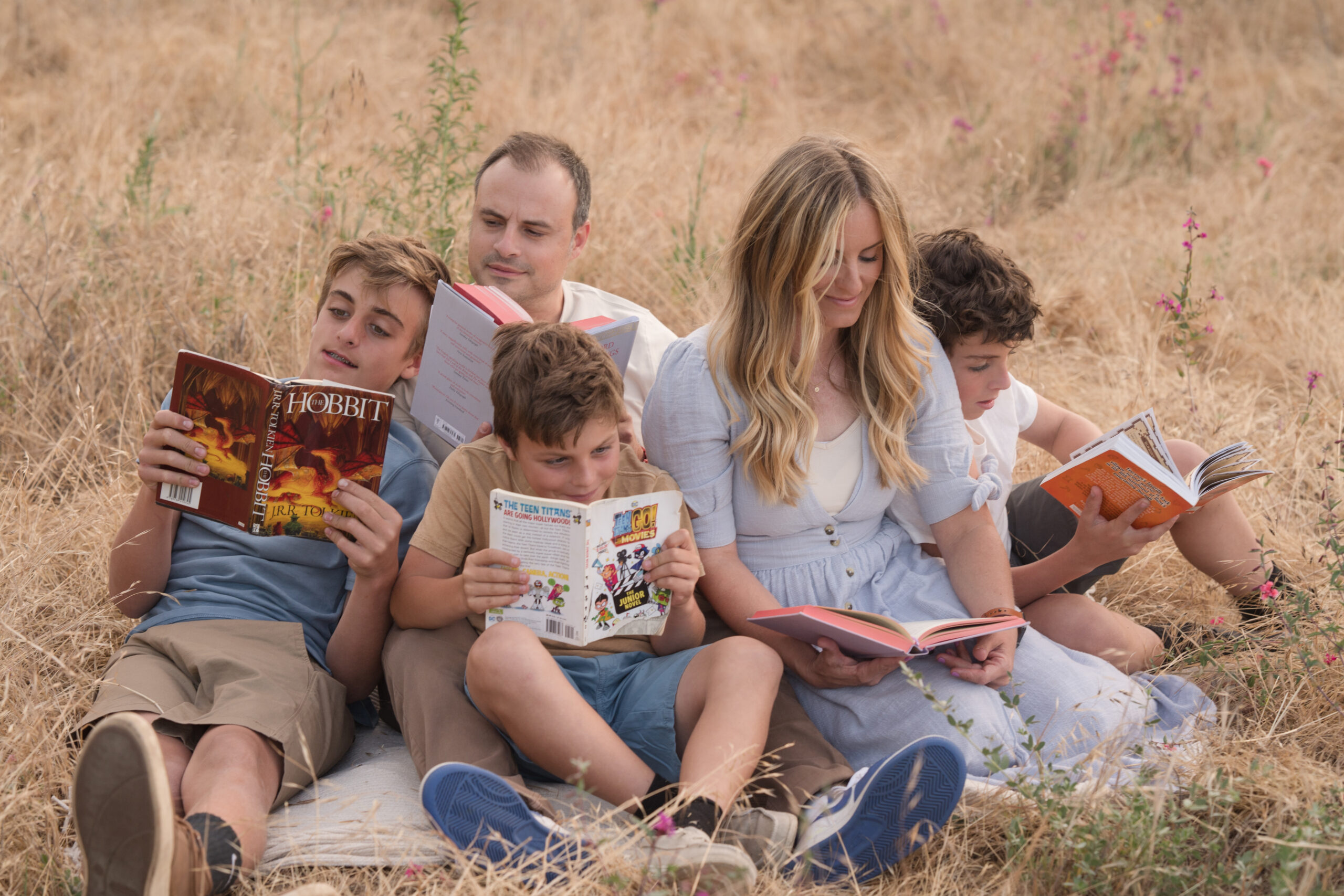 Family reading on a blanket for their candid session during golden hour in Oak Grove Park in Ripon, California