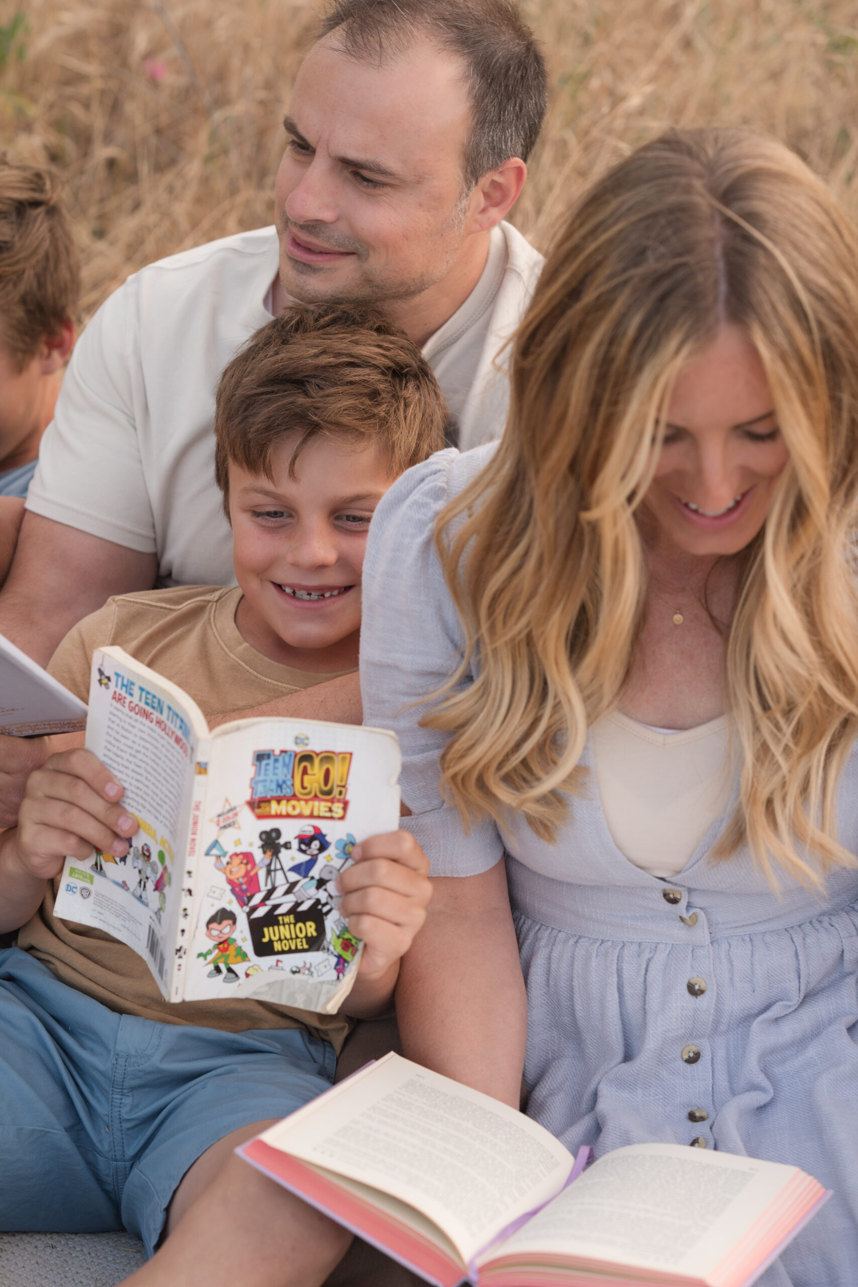 Family reading on a blanket for their candid session during golden hour in Oak Grove Park in Ripon, California