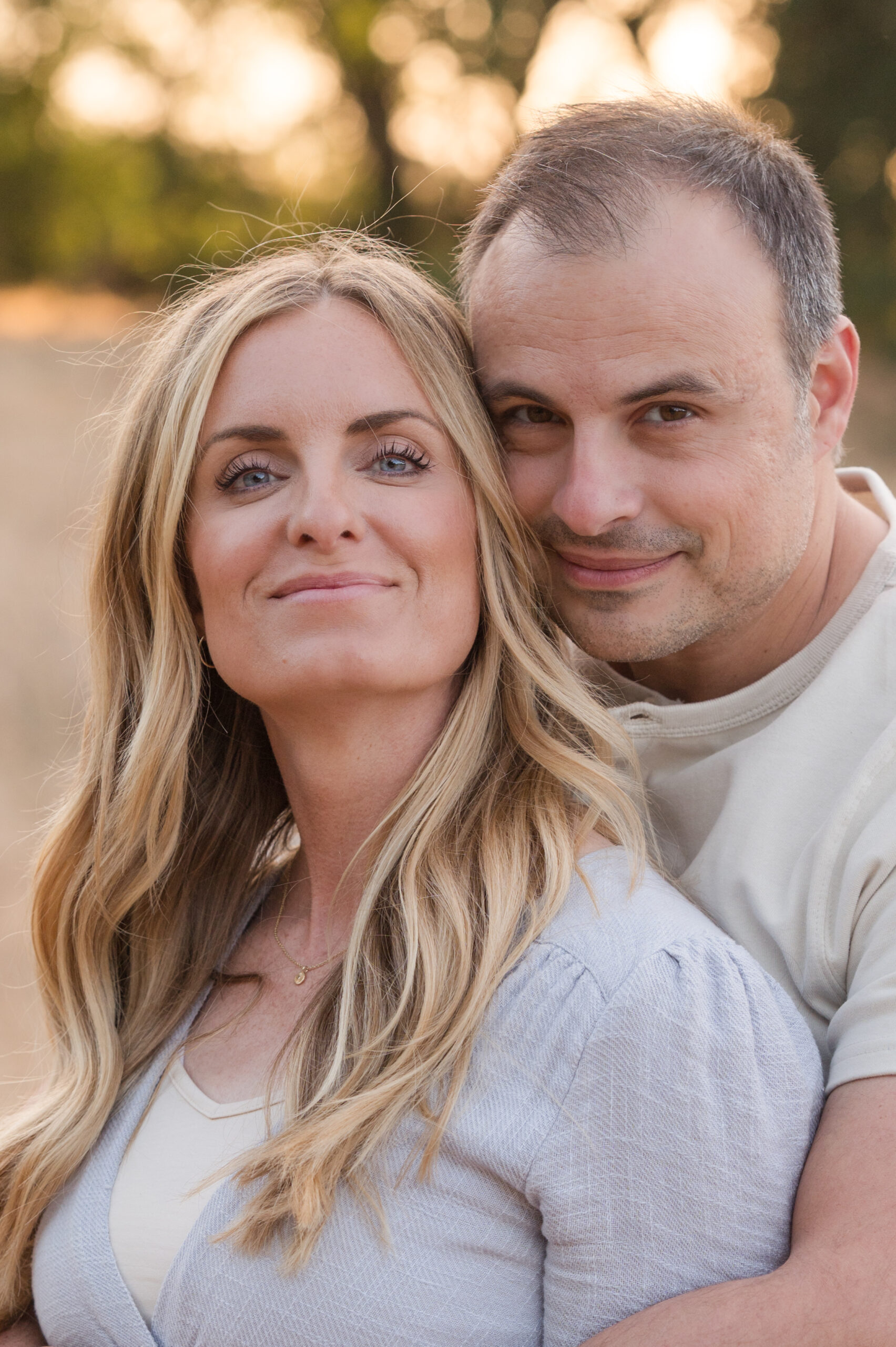 Husband and wife cozy up for their close up during golden hour at Oak Grove Park in Ripon, California