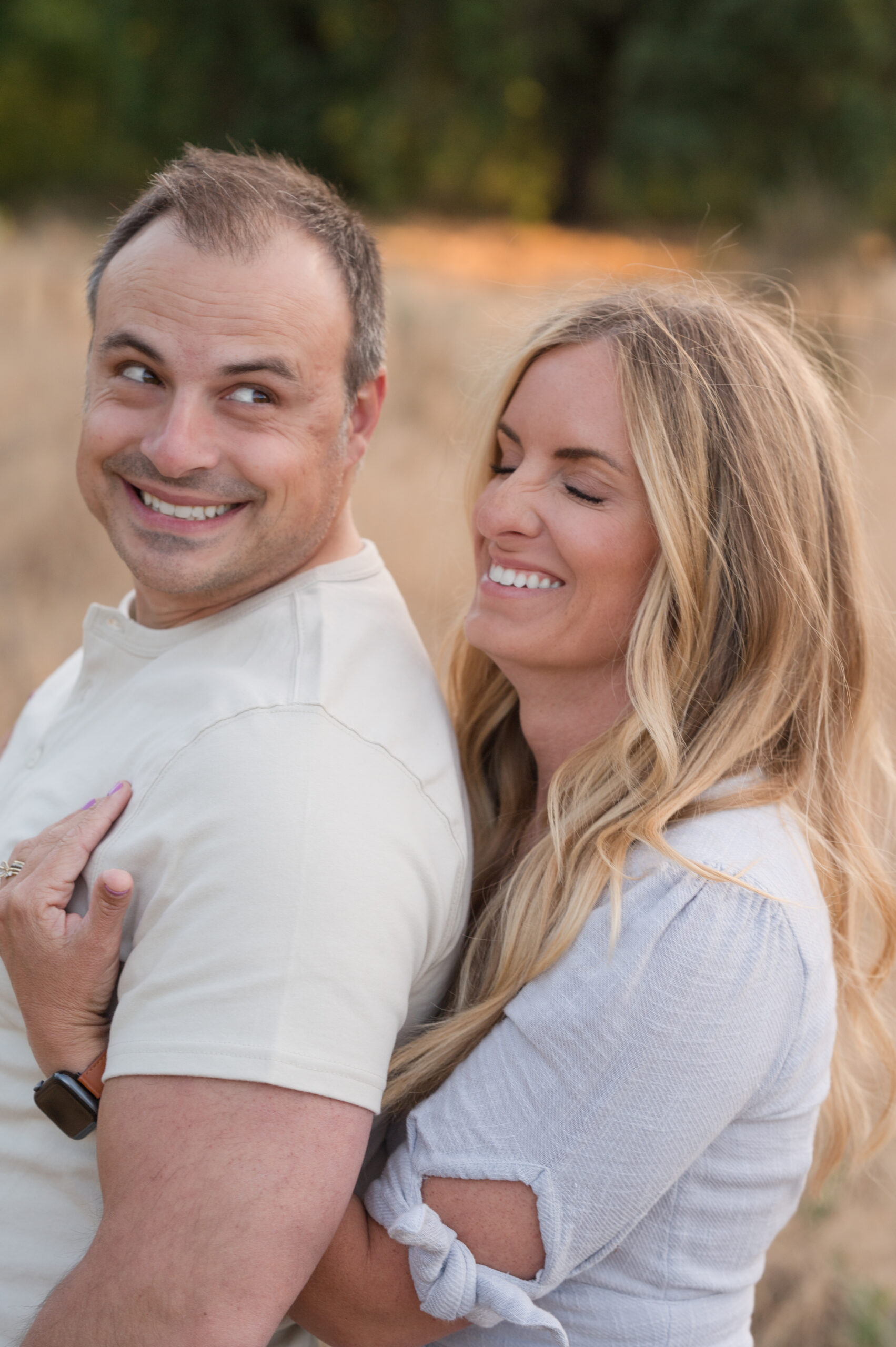Husband and wife caught in laughter during their family session at Oak Grove Park in Ripon, California.