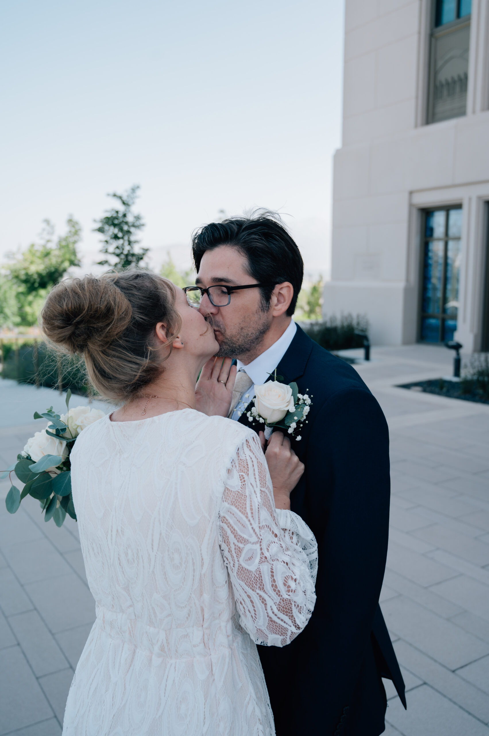 Bride steals a kiss before portraits on the temple grounds of the Saratoga Springs Utah LDS temple.