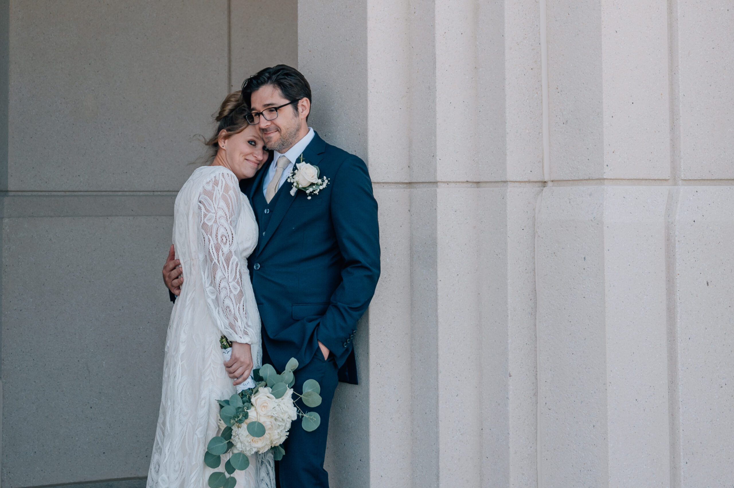 Bride and Groom at the LDS Saratoga Springs Temple in Utah. Groom holds onto his bride as she smiles at the camera with such ease and love.
