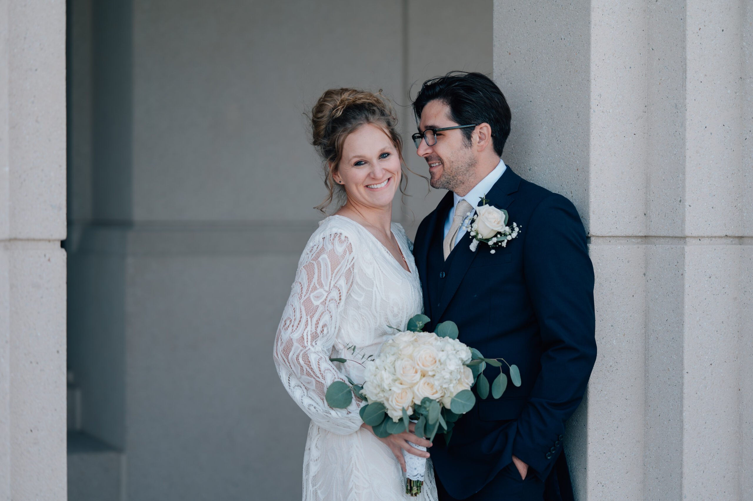 Groom steals a look at his bride while she smiles on.