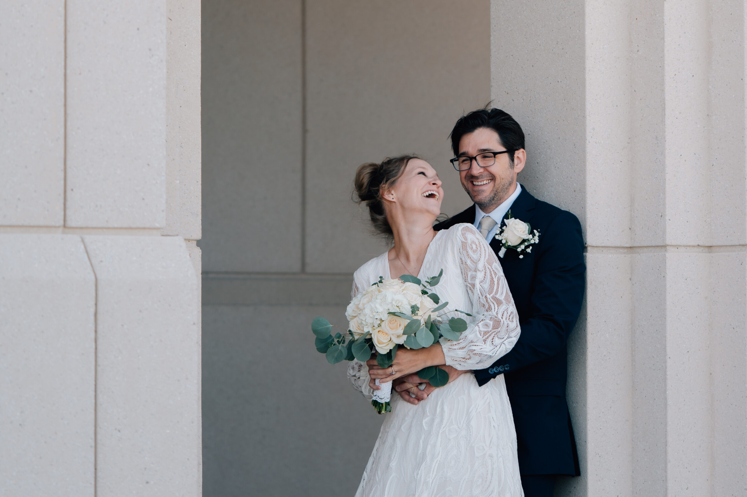 Bride and groom laughing in a framed doorway at the Saratoga Springs LDS Temple in Utah