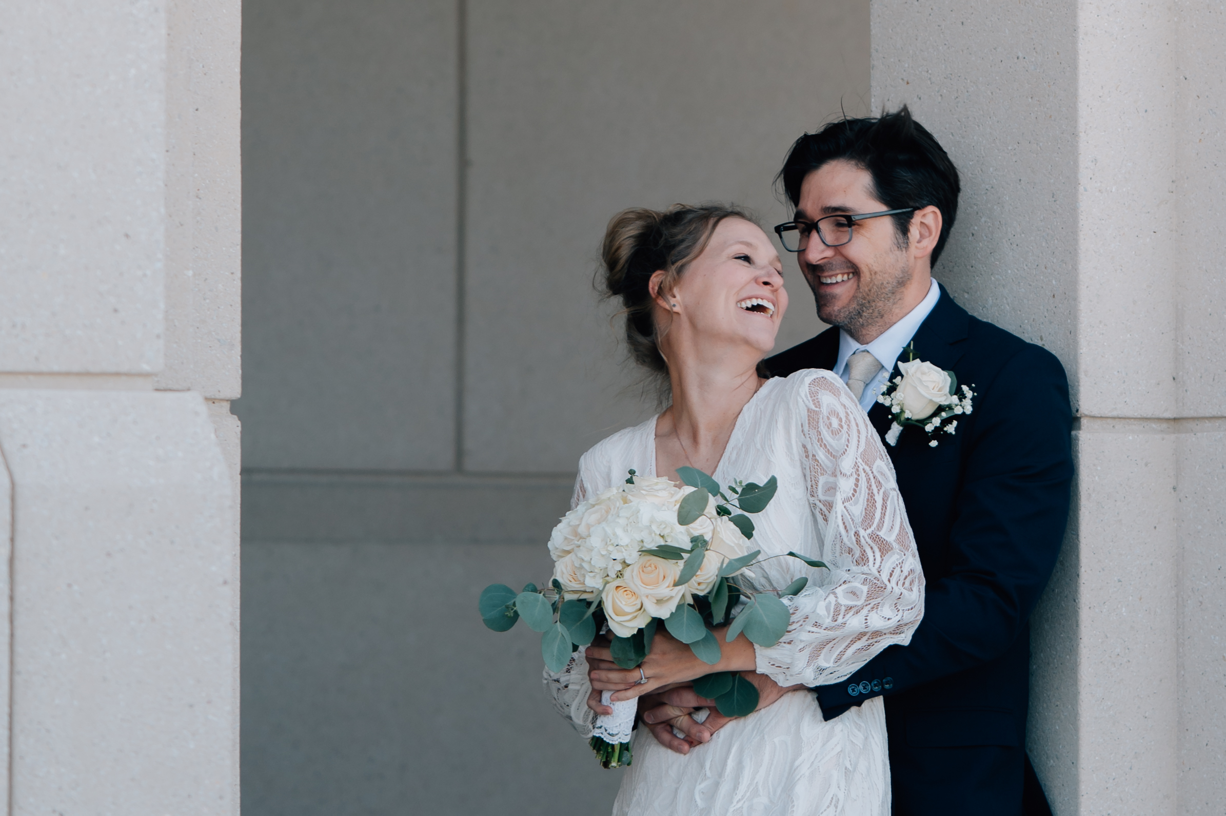 Bride and groom laughing in a framed doorway at the Saratoga Springs LDS Temple in Utah