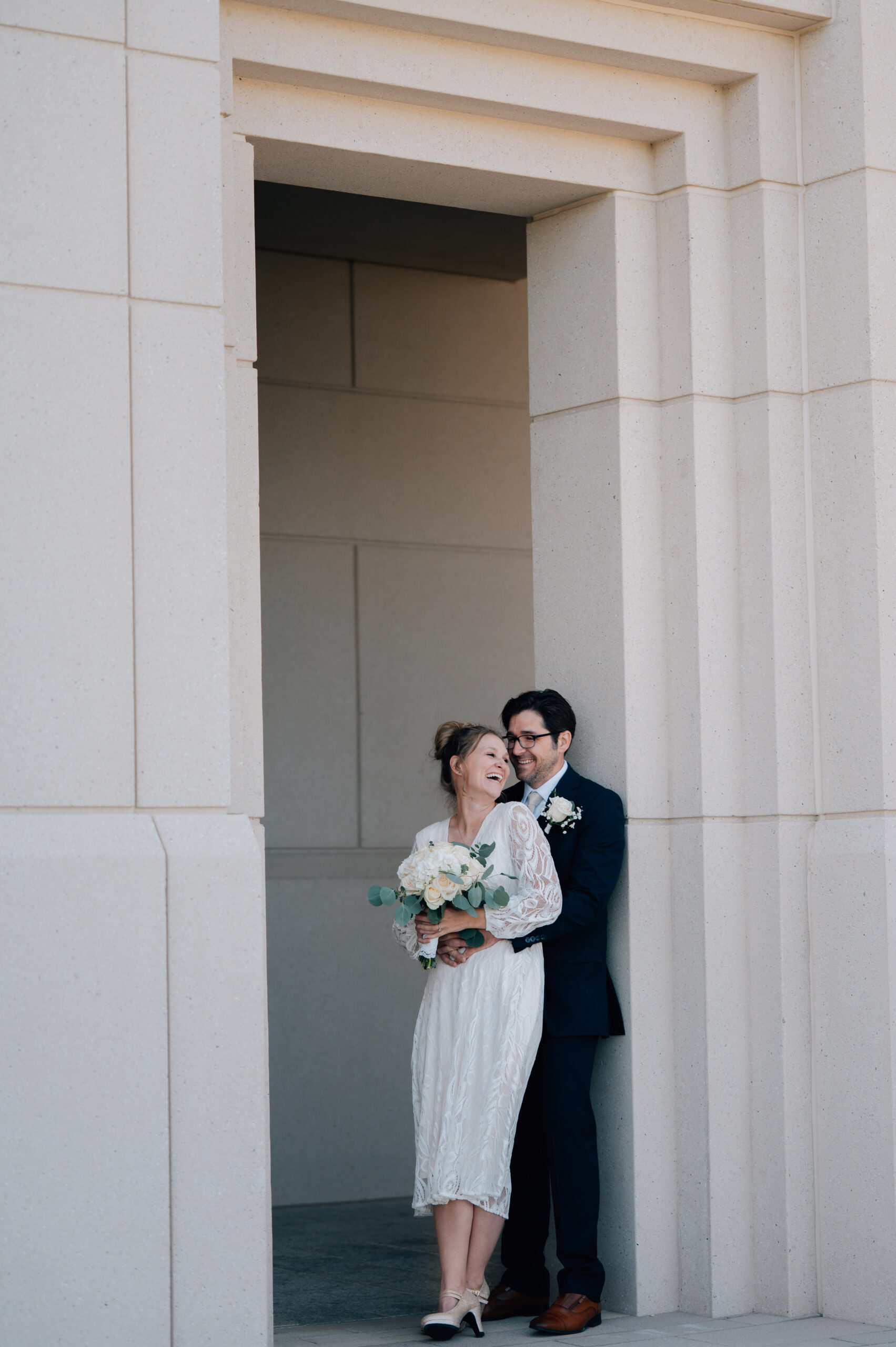 Bride and groom laughing in a framed doorway at the Saratoga Springs LDS Temple in Utah