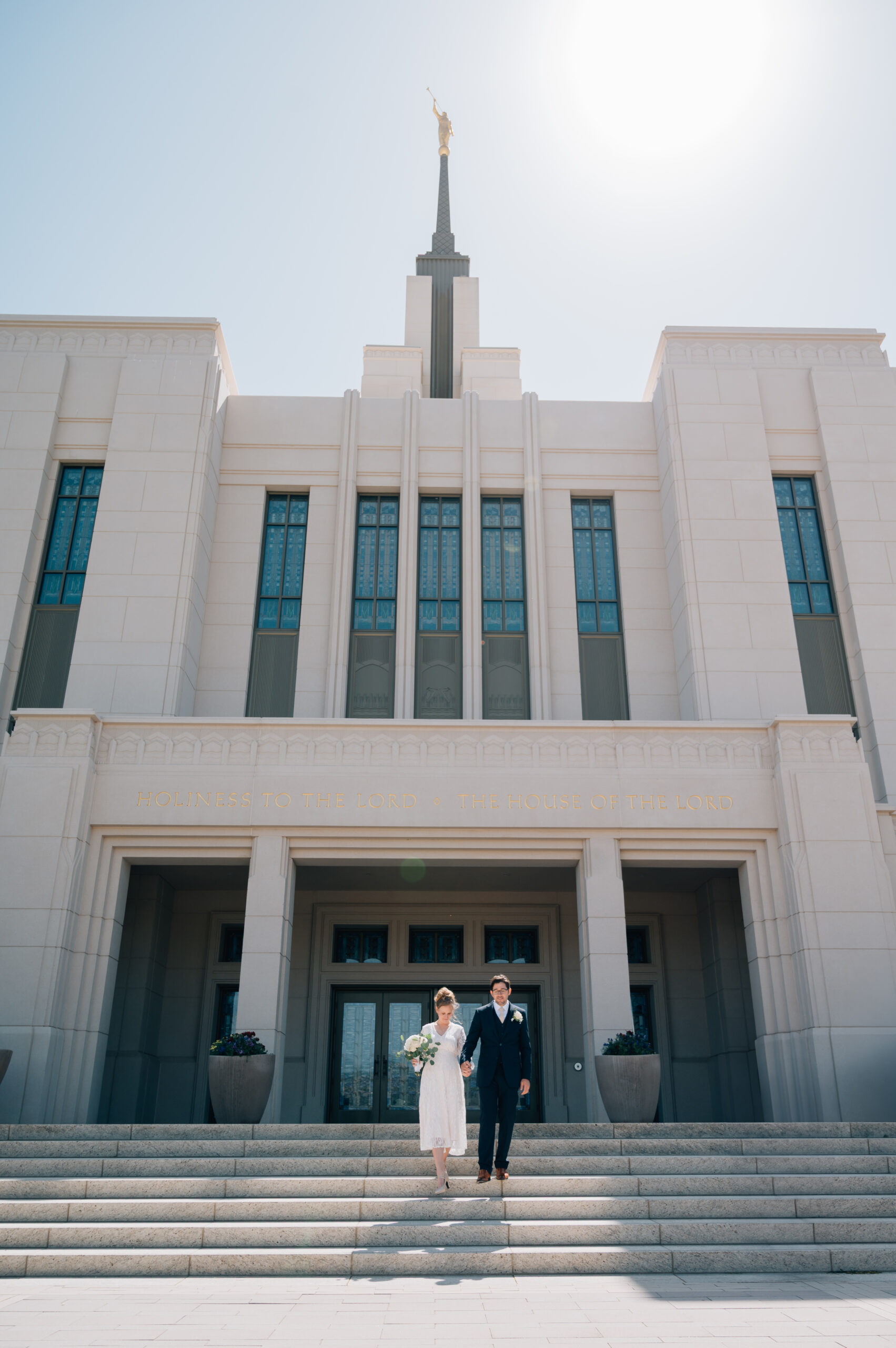 Bride and Groom walk hand in hand down the steps of the LDS temple in Saratoga Springs UT.