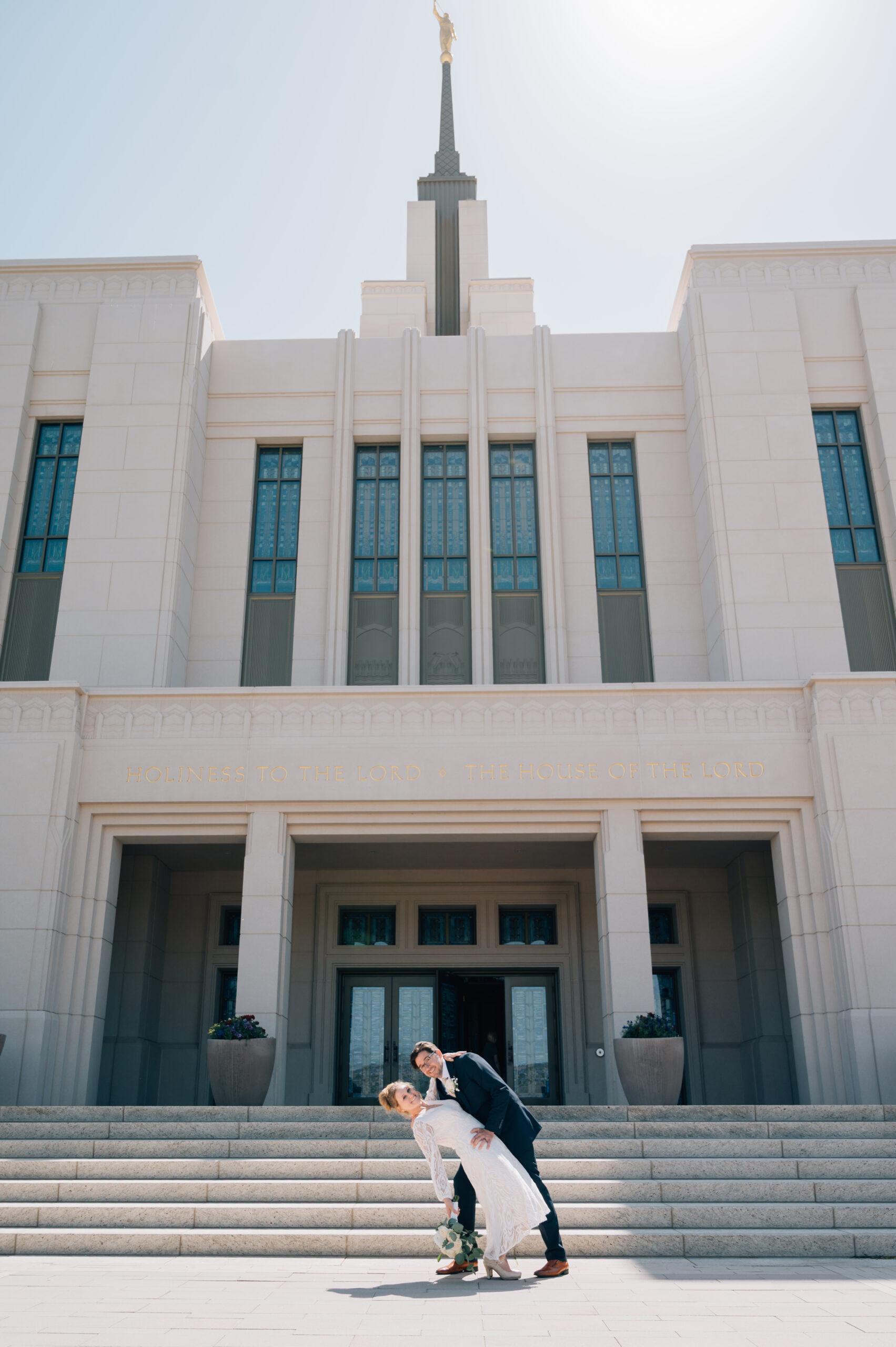 Groom dips his bride at the steps of the LDS temple in Saratoga Springs UT.