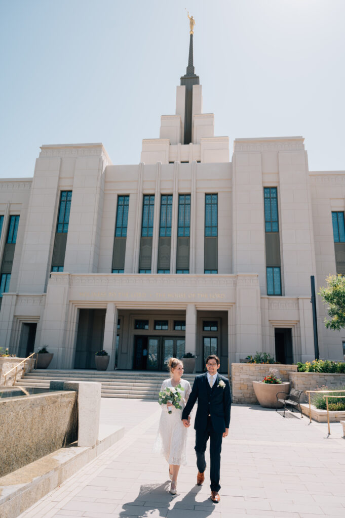 Bride and Groom walk hand in hand on the grounds of the LDS Temple in Saratoga Springs UT