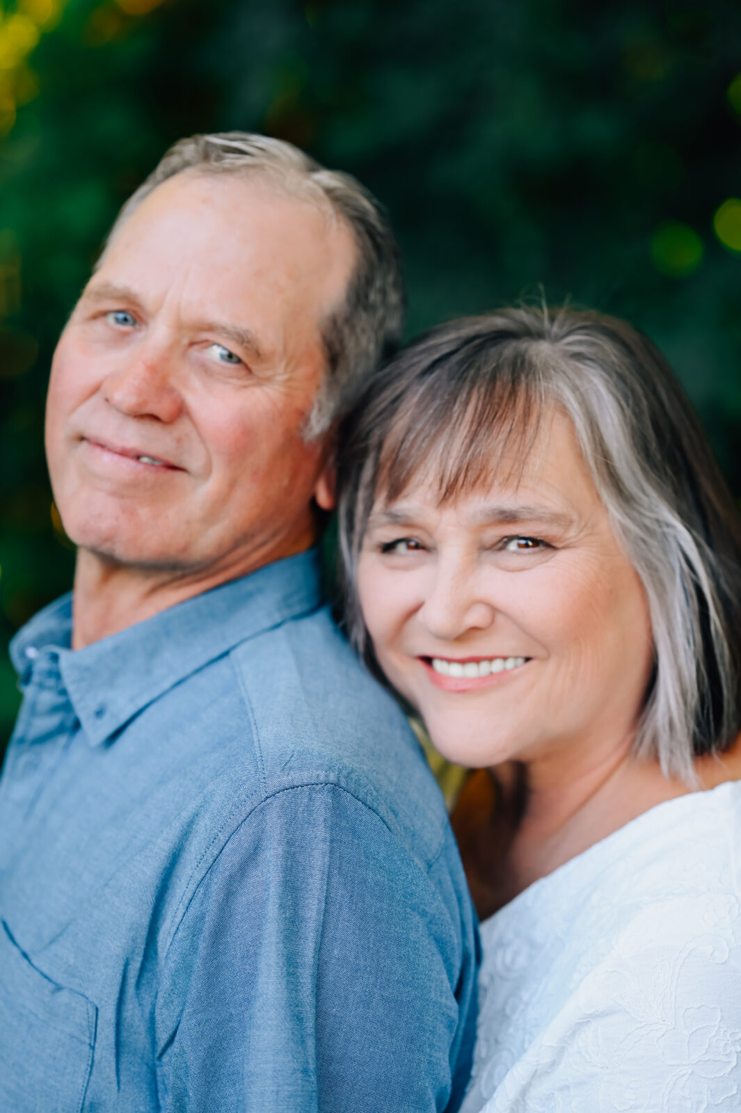 Grandma steals a hug on Grandpa from behind while looking on.