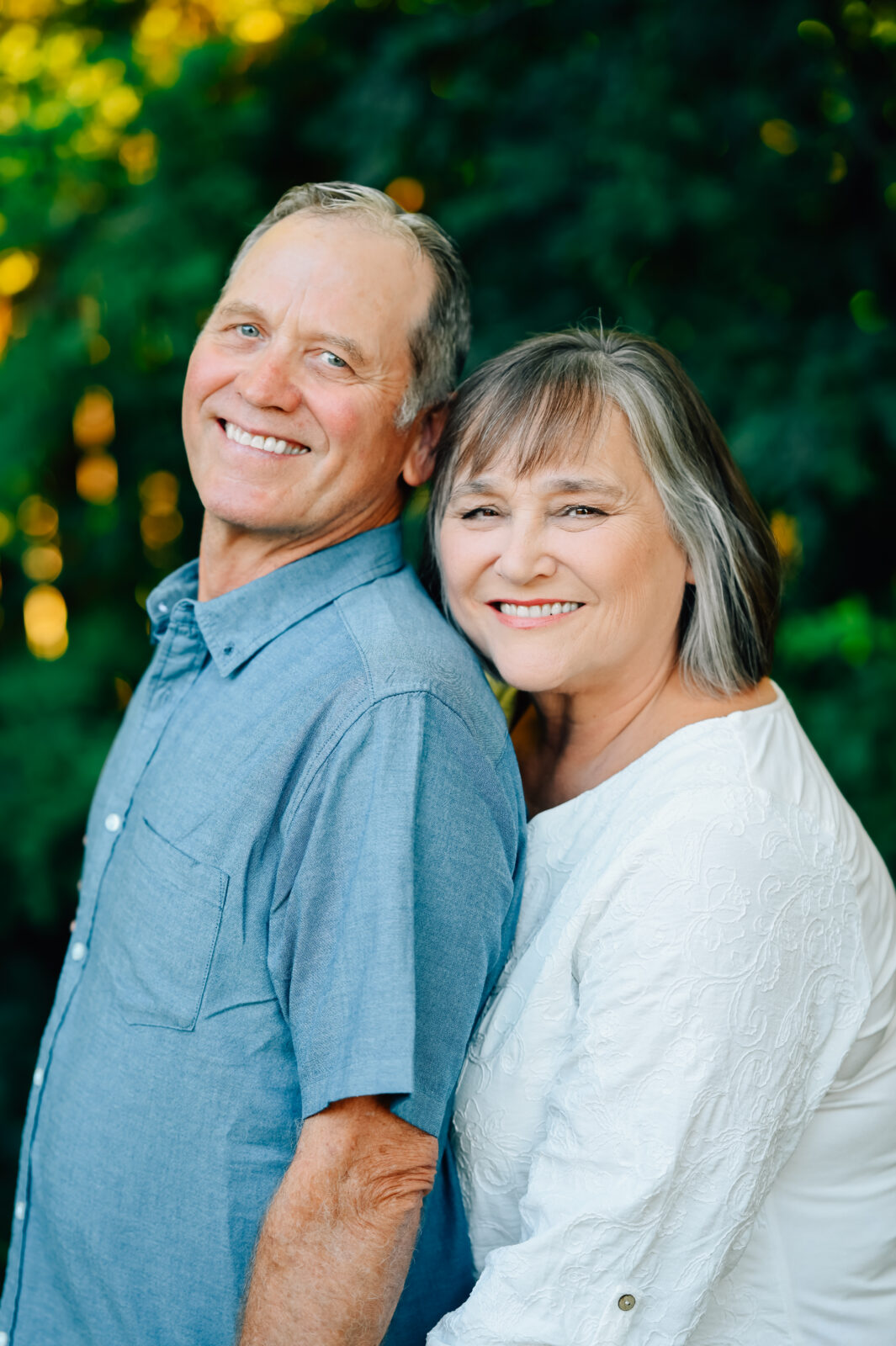 Grandma steals a hug on Grandpa from behind while looking on.