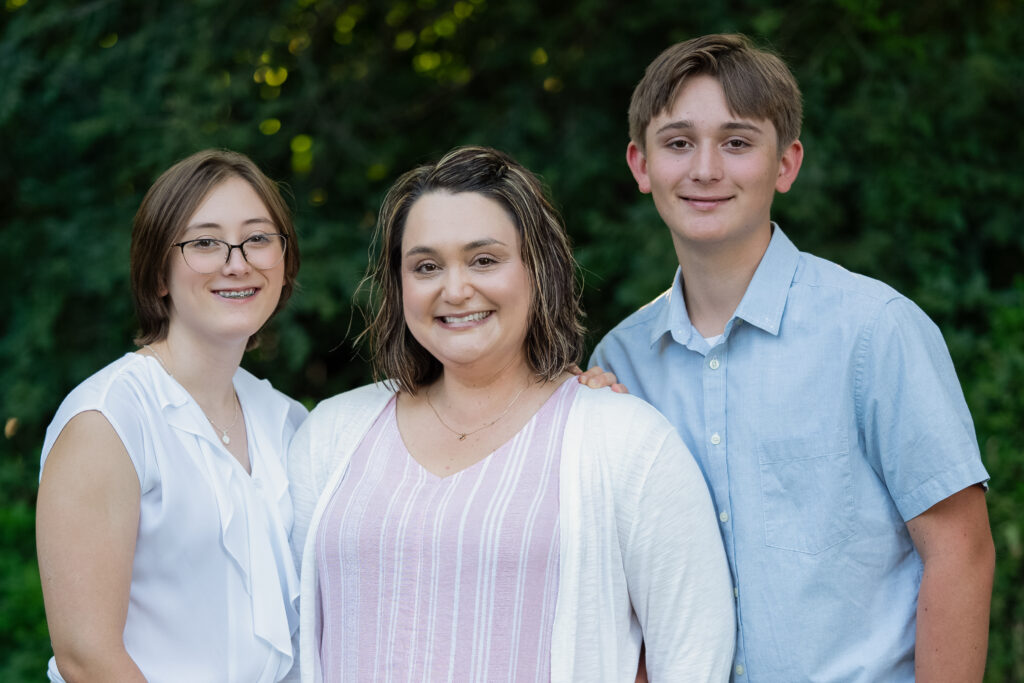 A sweet single Momma and her two kids with arms around each other while smiling on.