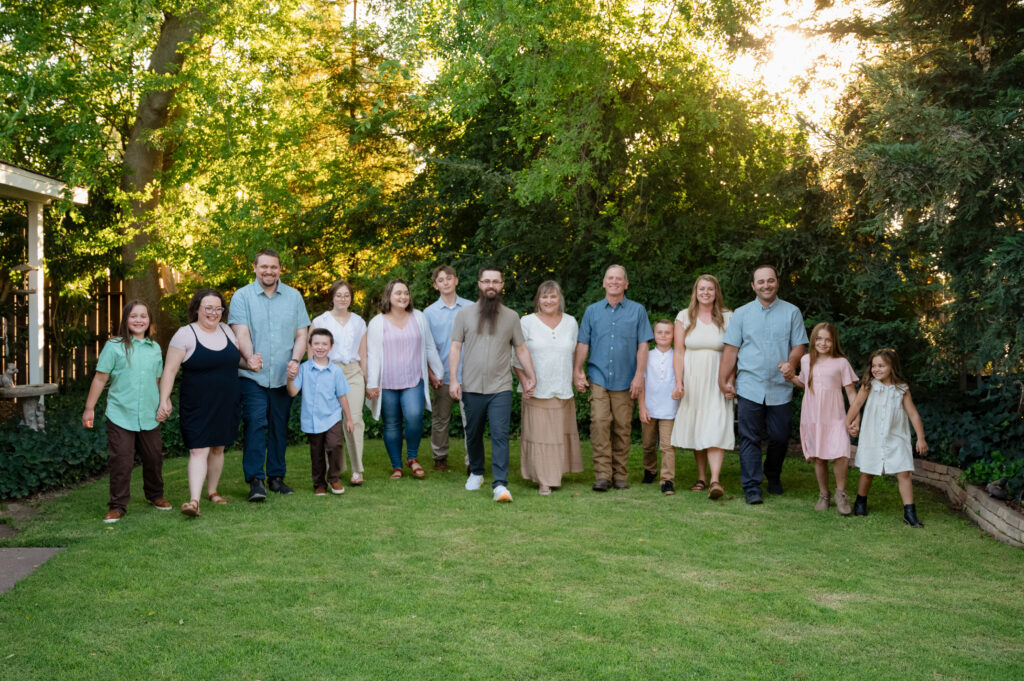 The entire family walking hand in hand through the front yard of Grandma & Grandpa's house. Everyone is laughing and looking at the camera.