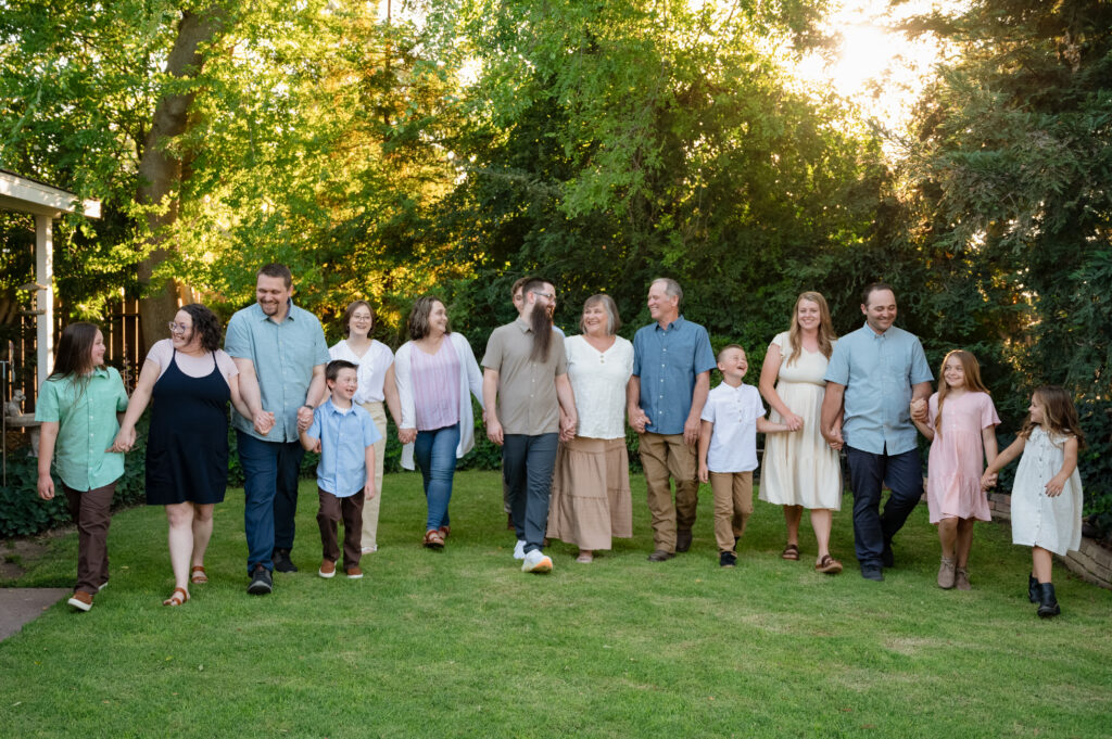 The entire family walking hand in hand through the front yard of Grandma & Grandpa's house. Everyone is laughing and looking at each other.