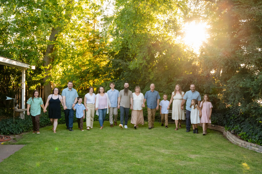 The entire family walking hand in hand through the front yard of Grandma & Grandpa's house. Everyone is laughing and looking at each other.