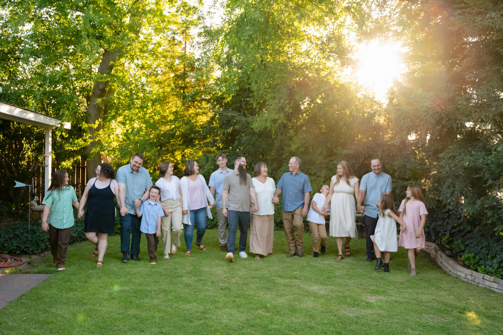 The entire family walking hand in hand through the front yard of Grandma & Grandpa's house. Everyone is laughing and looking at each other.