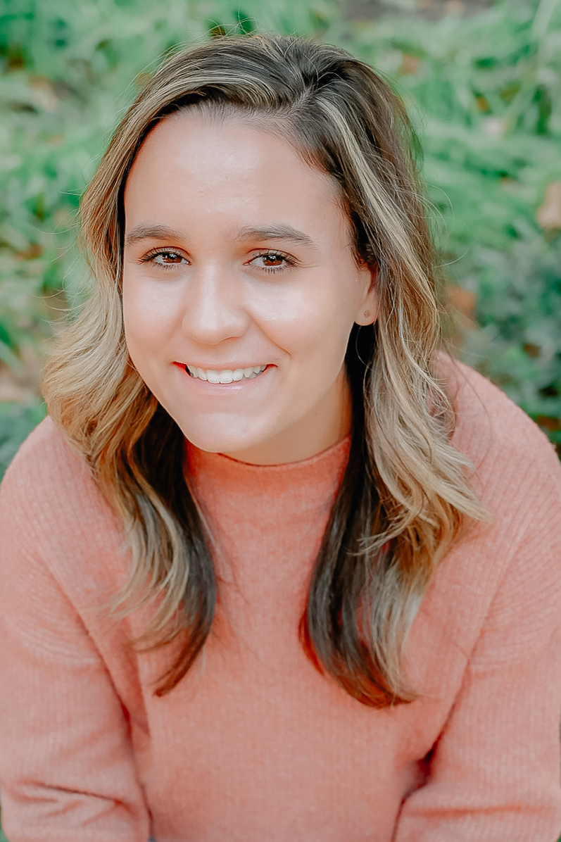 A senior girl smiling brightly for the camera in a close up shot.