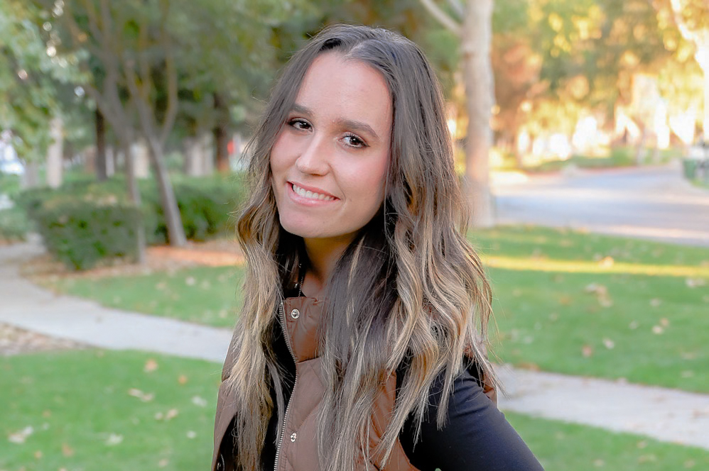 A senior girl smiling brightly for the camera in a close up shot.