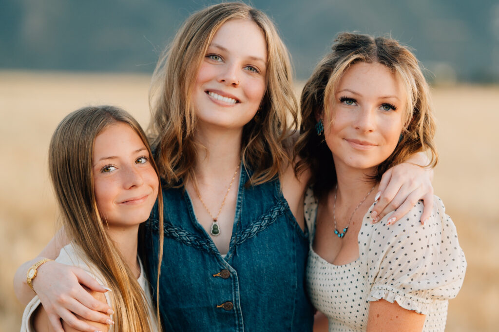 A graduating senior smiles with her two sisters in Mapleton, UT