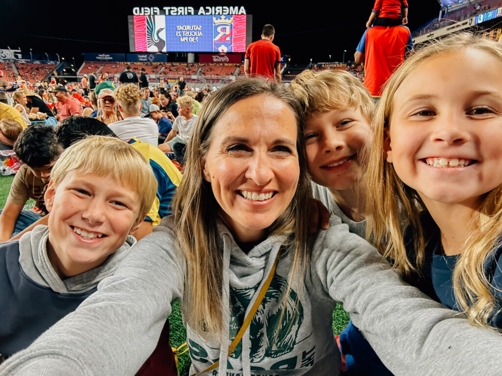 A mom smiles with her three young kids while sitting on the pitch at Real Salt Lake.