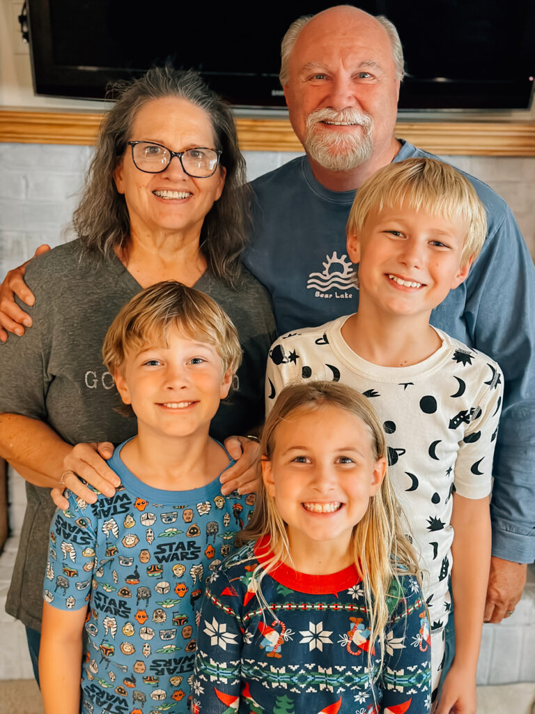 Grandma and Grandpa smiling on with their three grandkids standing in front of them in North Orem, UT. 