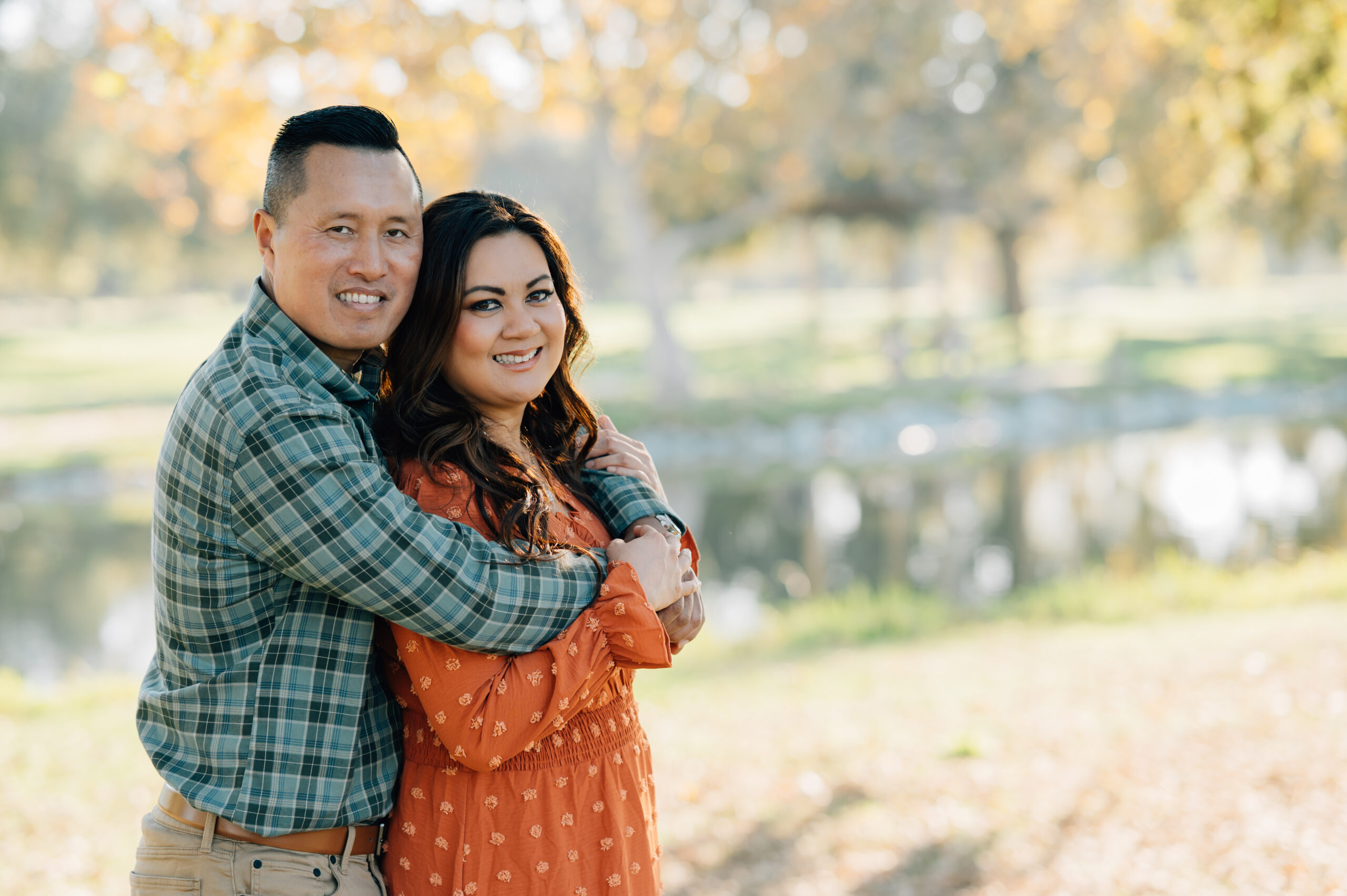 Capital posing together by the lake at Oak Grove Park during a fall family photo session