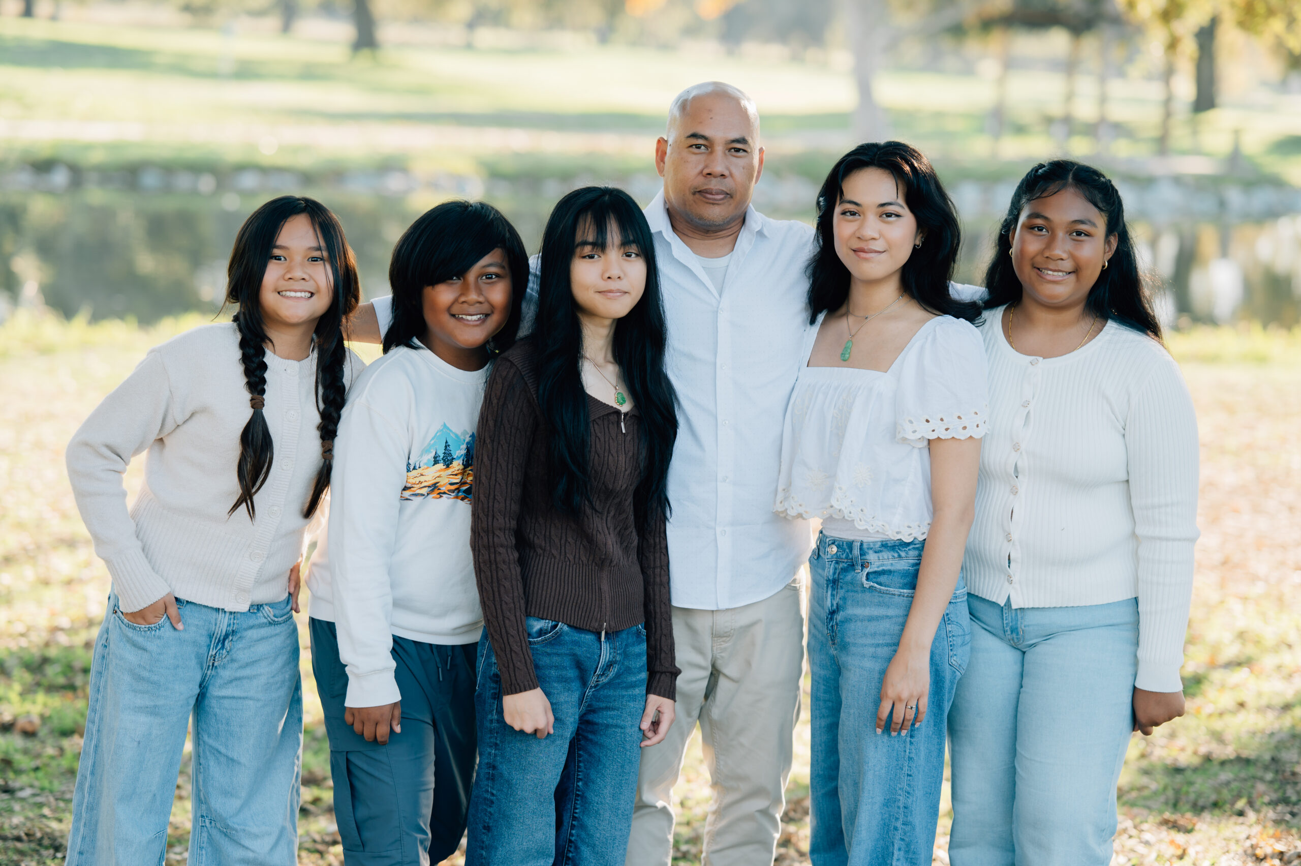 Uncle posing with his nieces and nephew by the lake at Oak Grove Park during a fall family photo session