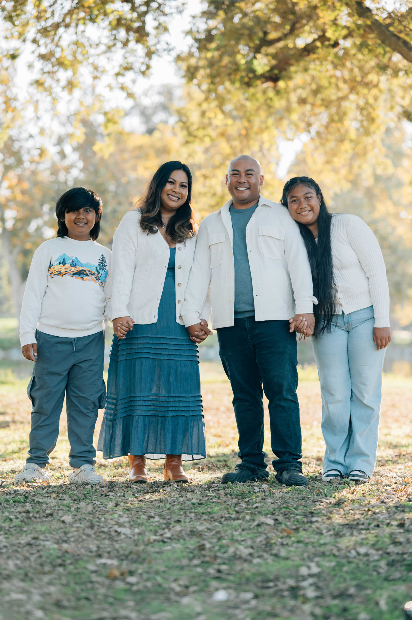 Family of four posing together by the lake at Oak Grove Park during a fall family photo session