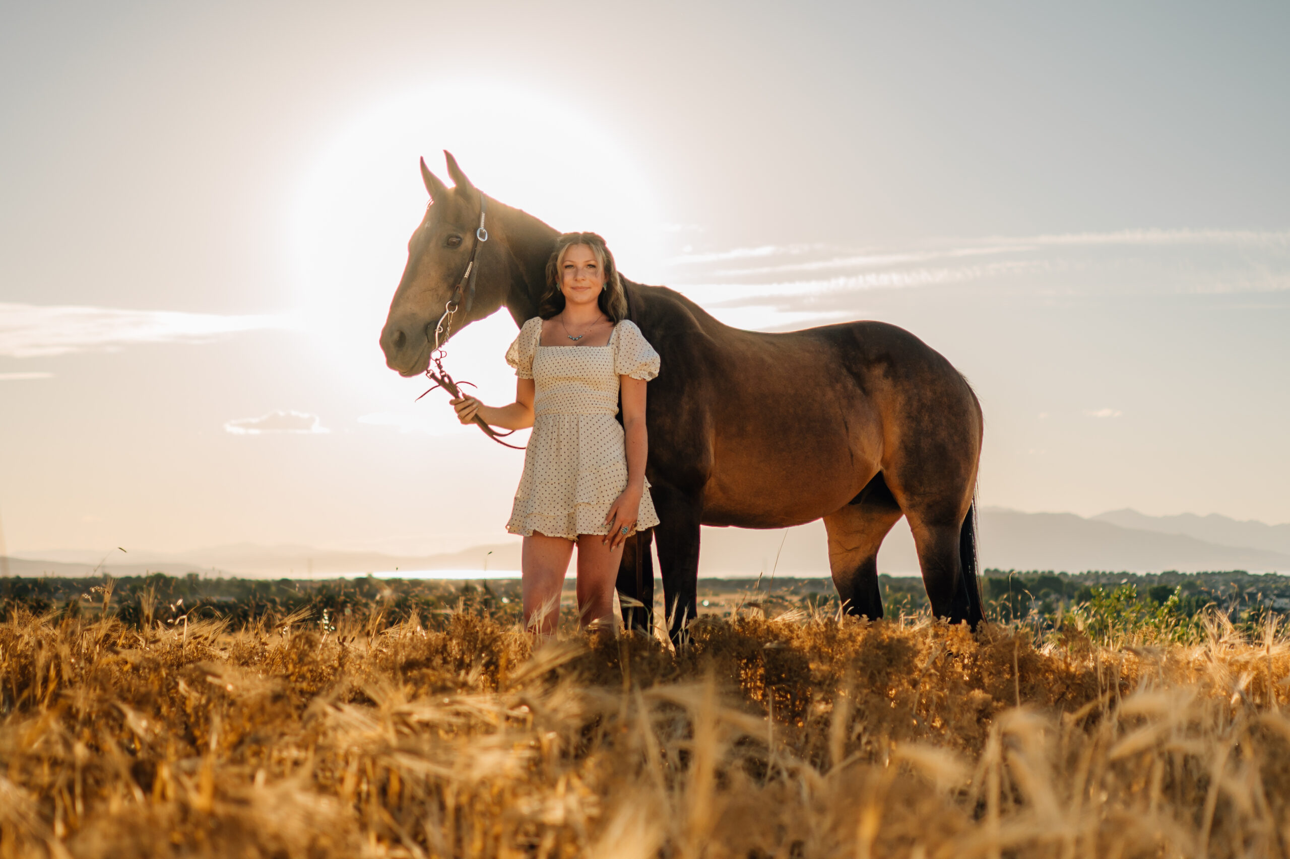 Just a girl with her horse. As the sun is setting a girl stands in front of her horse smiling on.