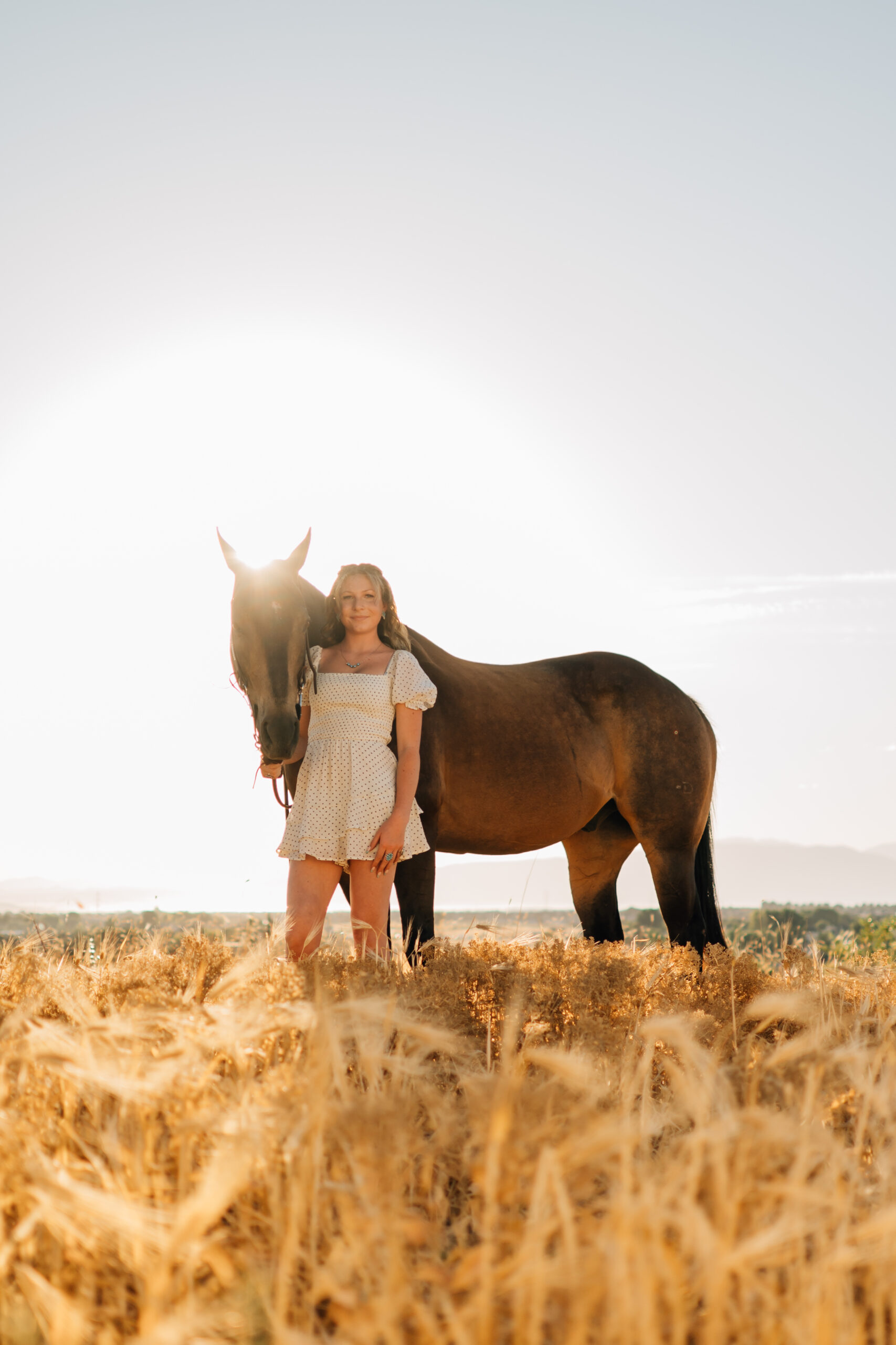 Just a girl with her horse. As the sun is setting a girl stands in front of her horse smiling on.