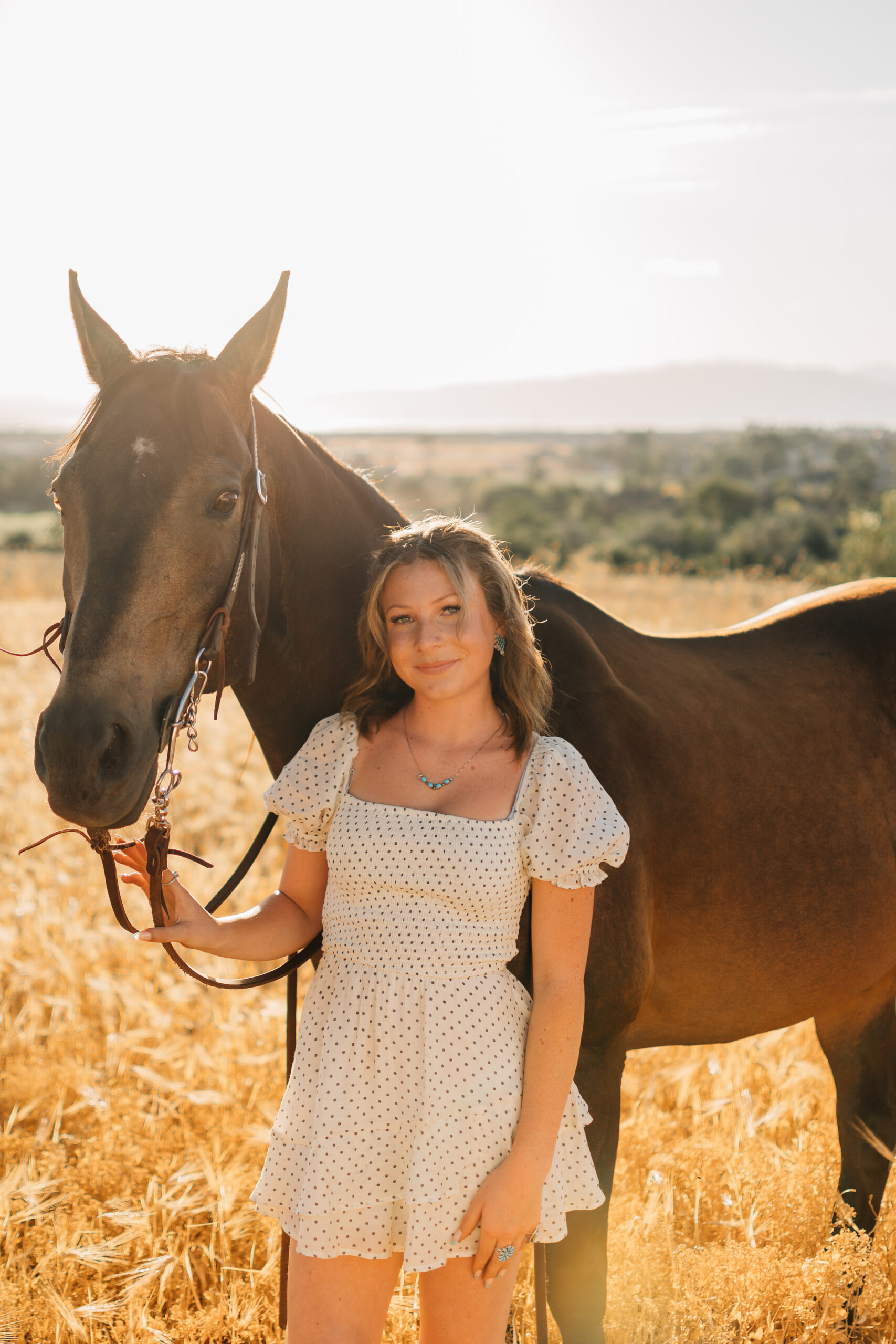 Just a girl with her horse. As the sun is setting a girl stands in front of her horse smiling on.